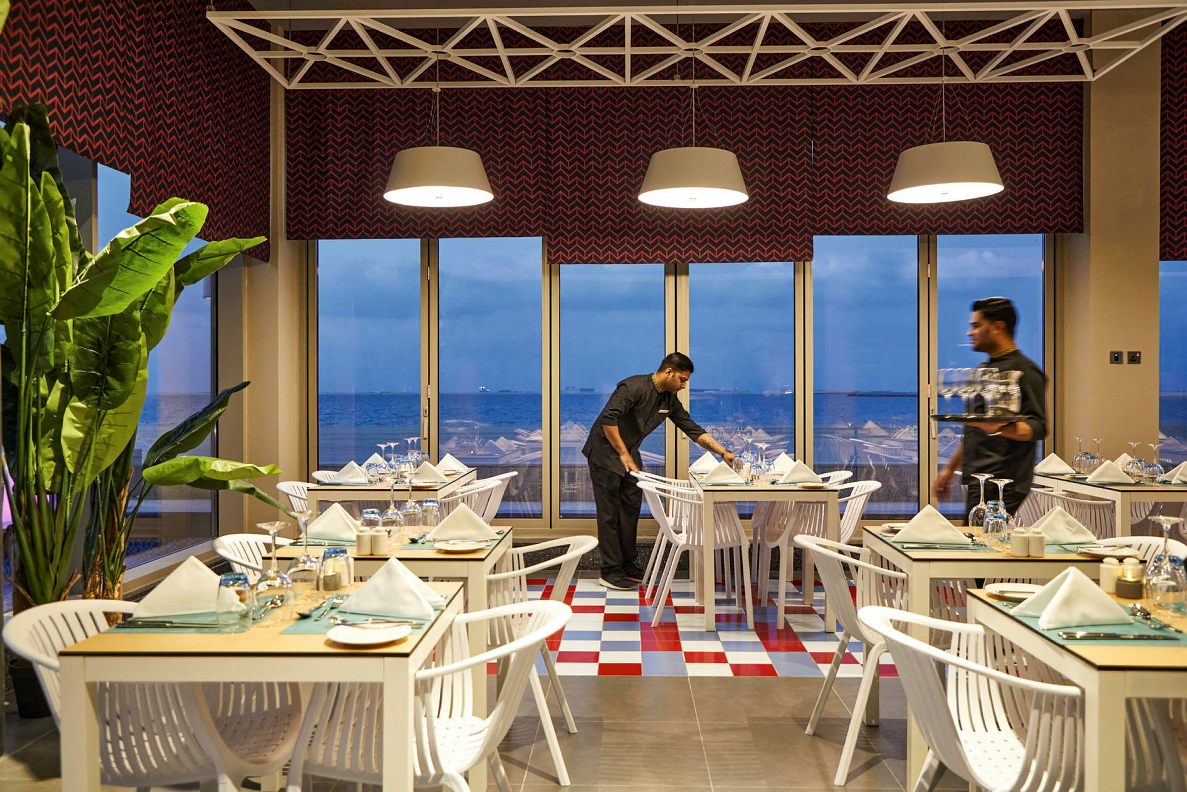 En lys restaurant med dekkede bord og panoramautsikt over havet gjennom store vinduer. (AI-generert tekst)
