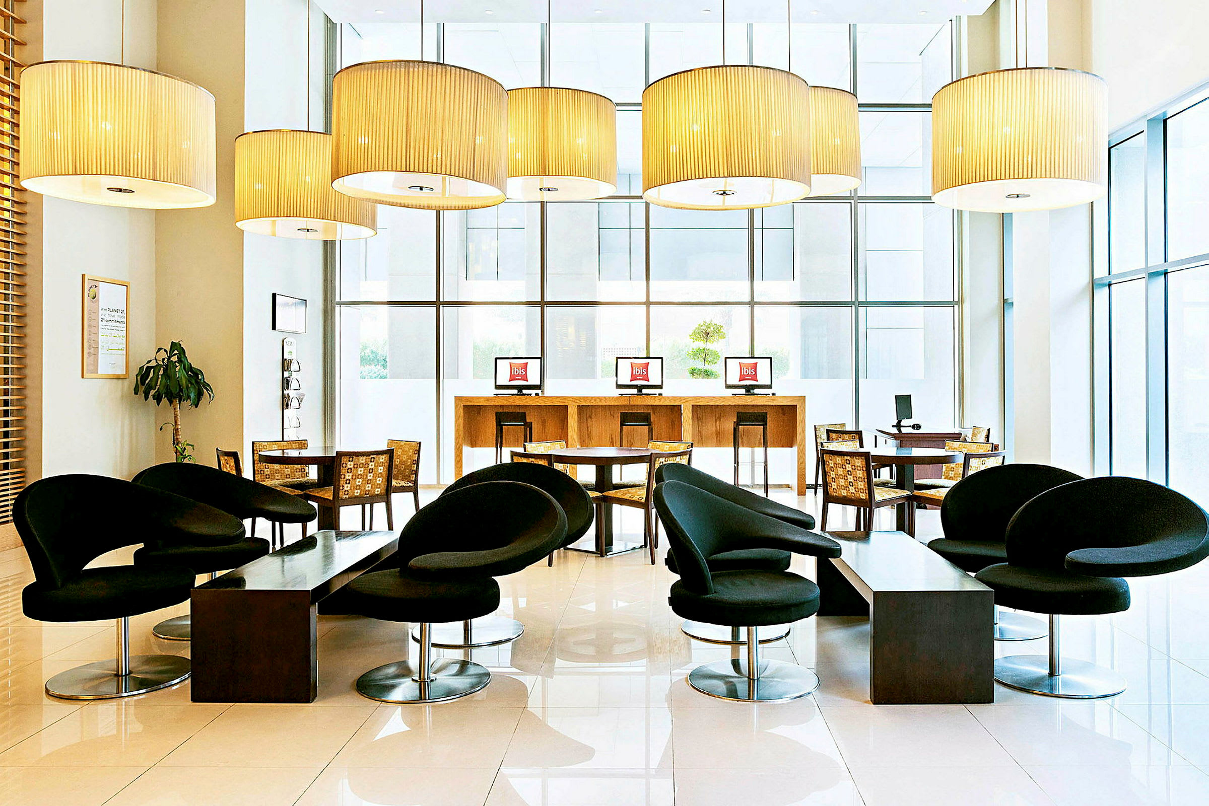 En moderne møblert hotellobby med svarte stoler, bord og datamaskinstasjoner. (AI-generert tekst)