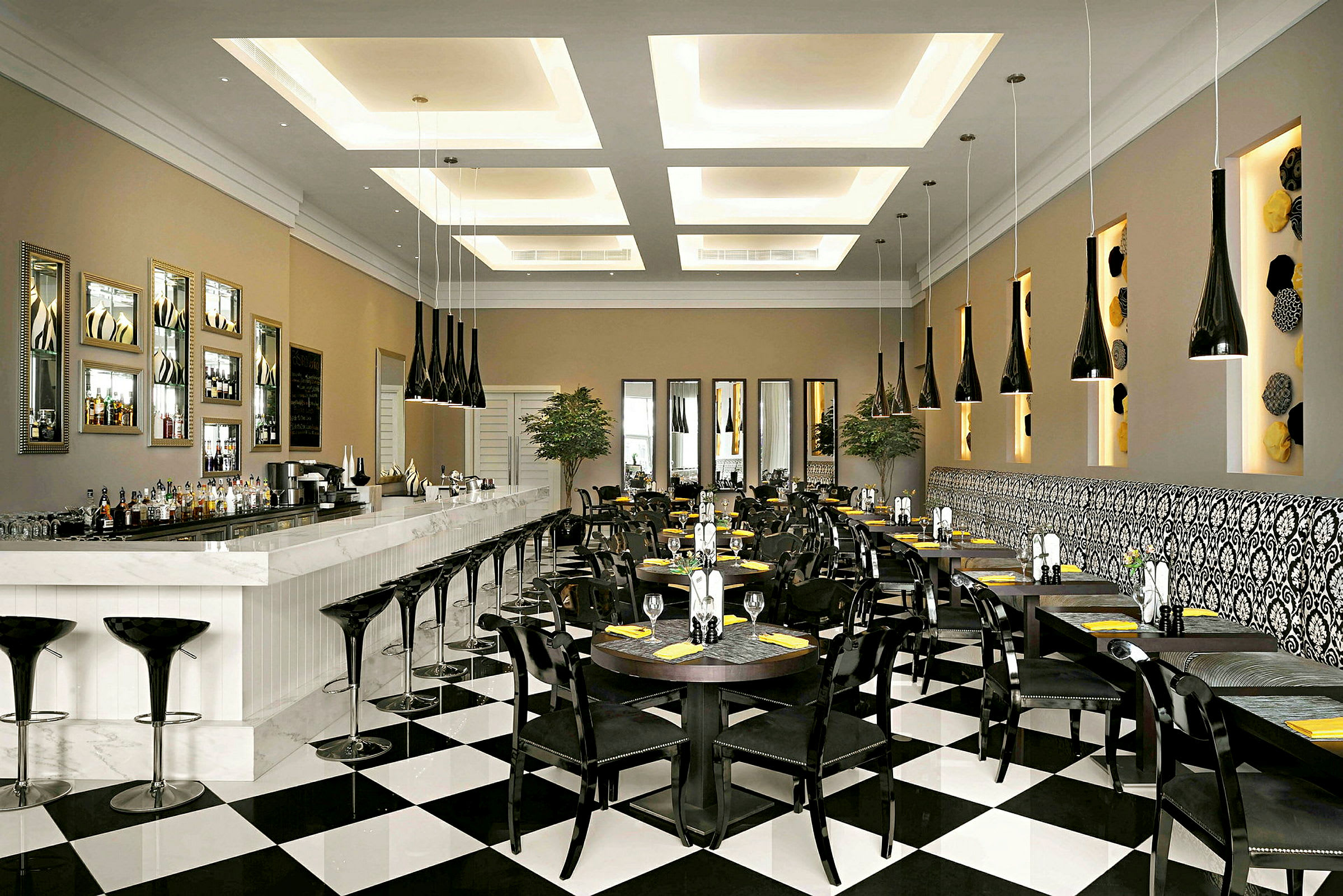 En elegant restaurant eller kafé med en lang hvit bardisk, svarte stoler, bordoppsett og særpreget moderne innredning. (AI-generert tekst)