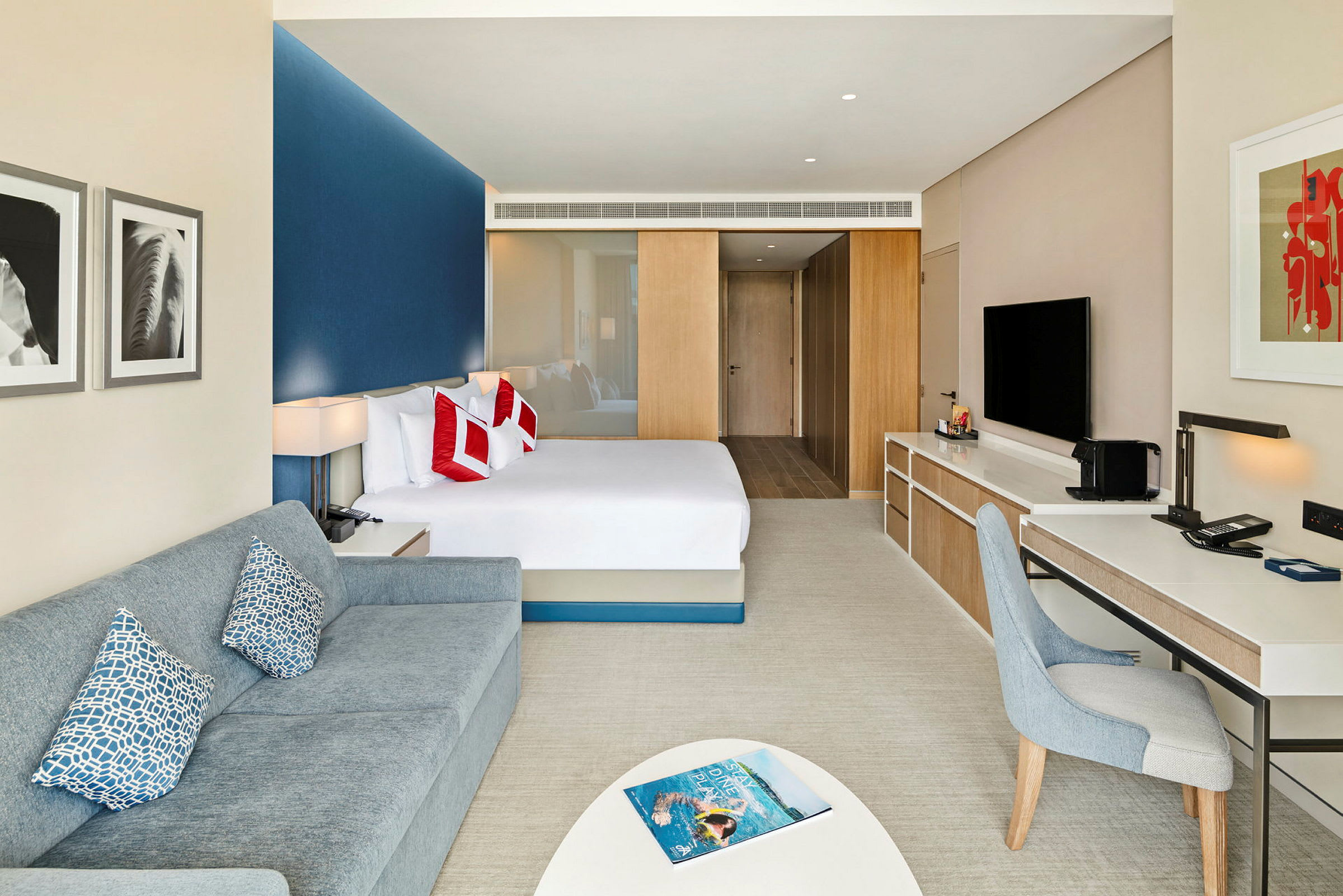 Moderne hotellrom med seng, sofa og skrivebord. (AI-generert tekst)
