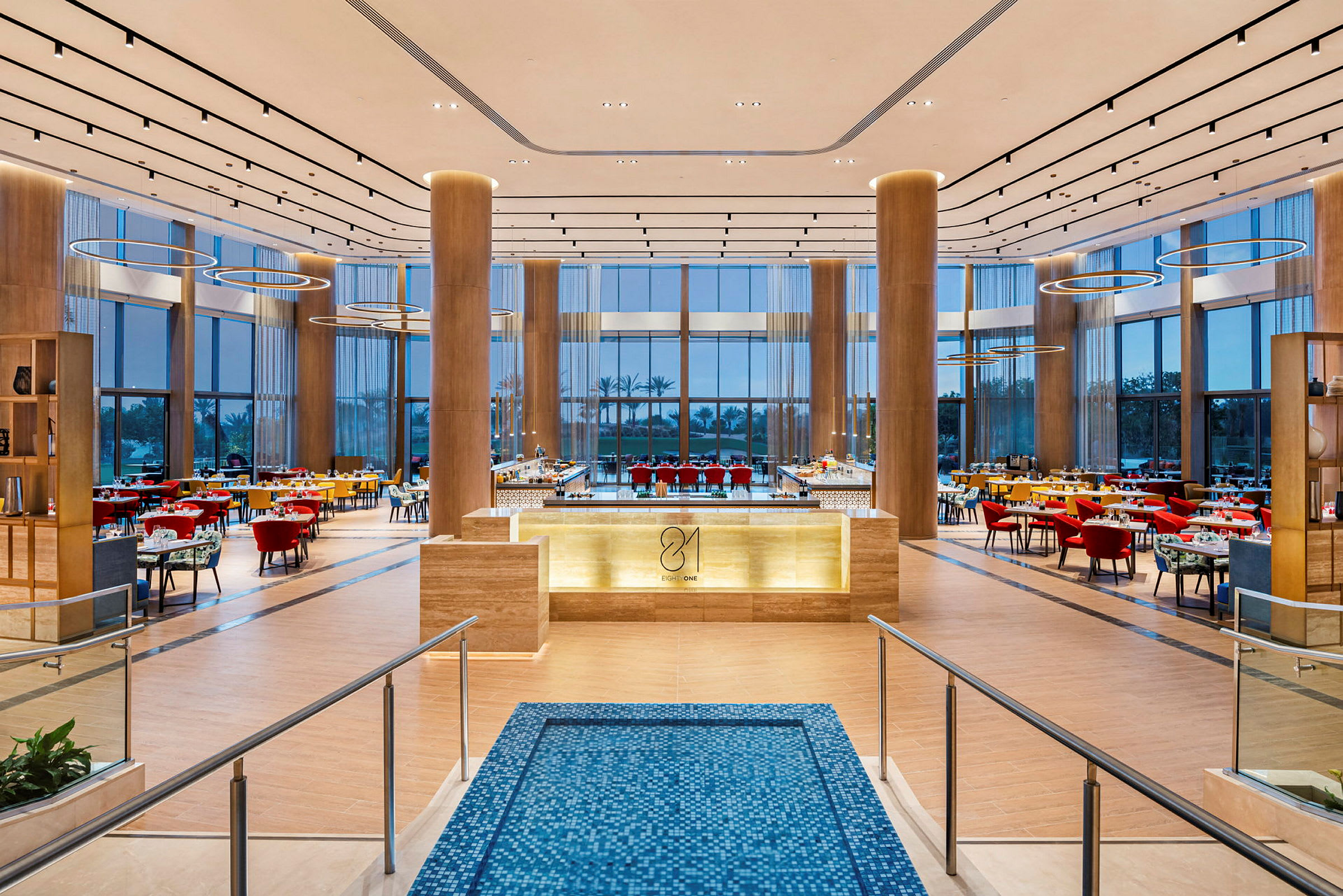 En stor og elegant restaurant med moderne møbler er godt belyst. Det er bord og stoler plassert rundt lokalet. (AI-generert tekst)