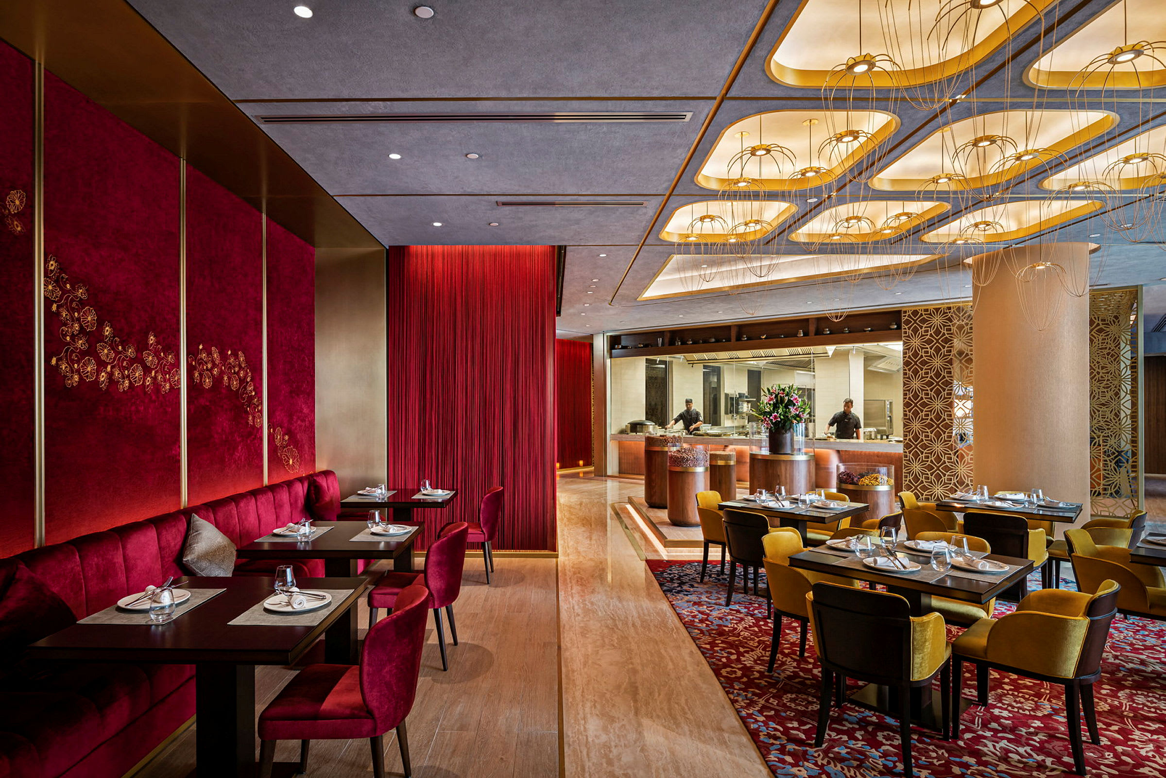 En elegant restaurant med røde og gule sitteplasser, vakkert dekorerte tak og et åpent kjøkken. (AI-generert tekst)