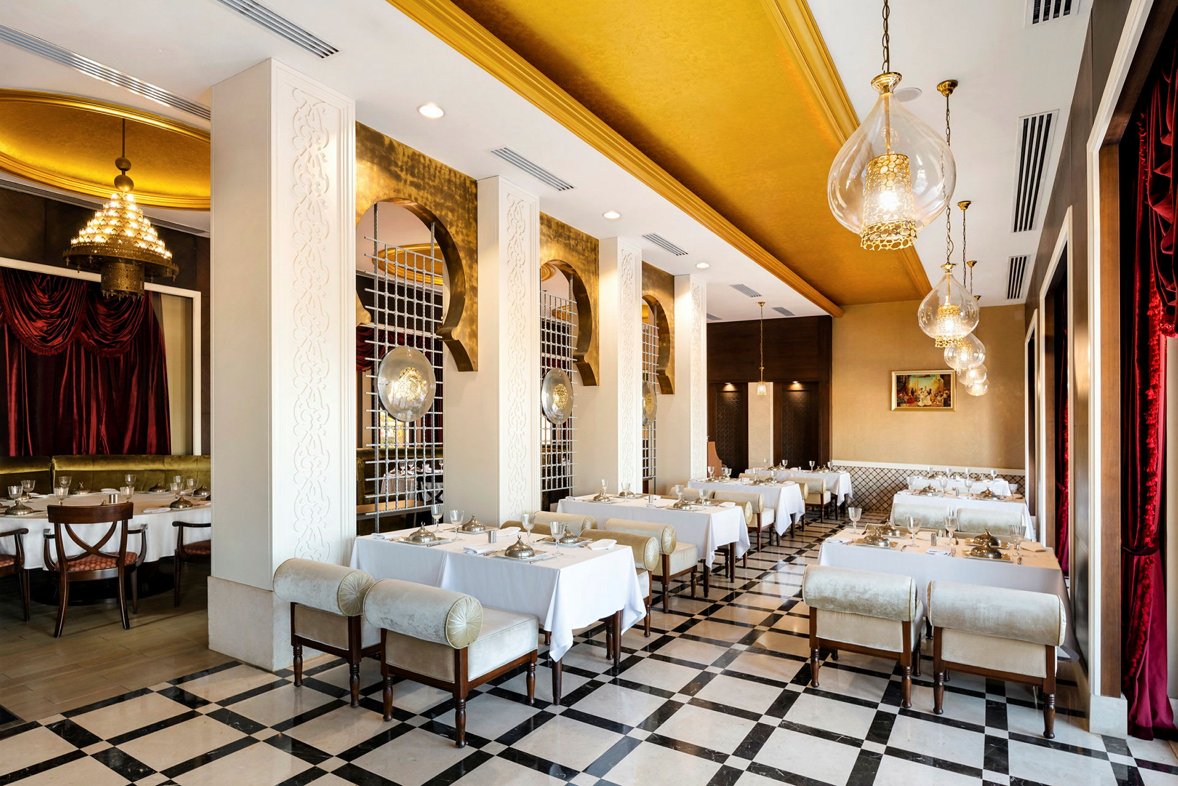 En elegant restaurant med gulldetaljer og hvite duker på bordene. (AI-generert tekst)