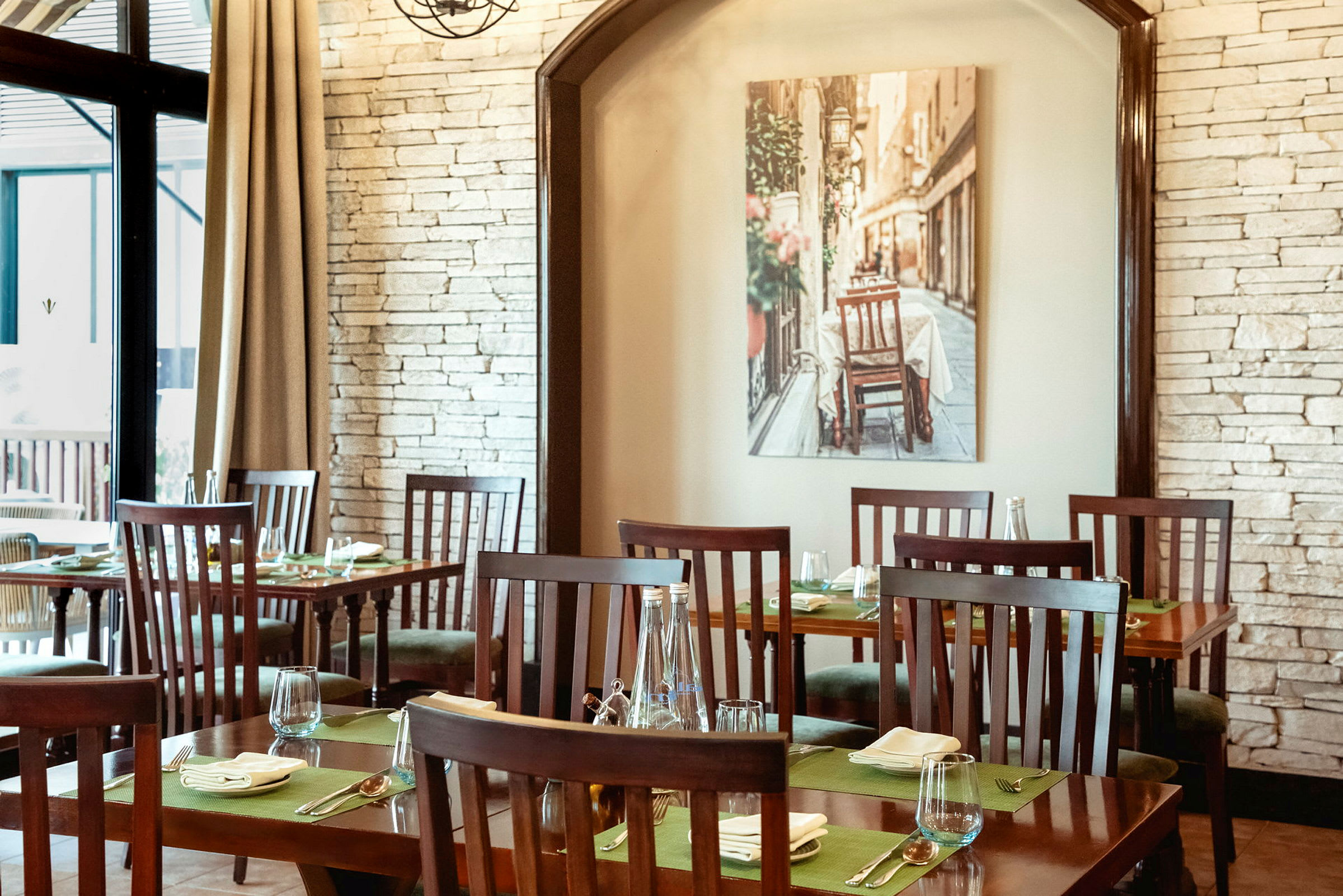 Interiøret i en restaurant med tremøbler og dekkede bord, med et bilde på veggen av en gate. (AI-generert tekst)