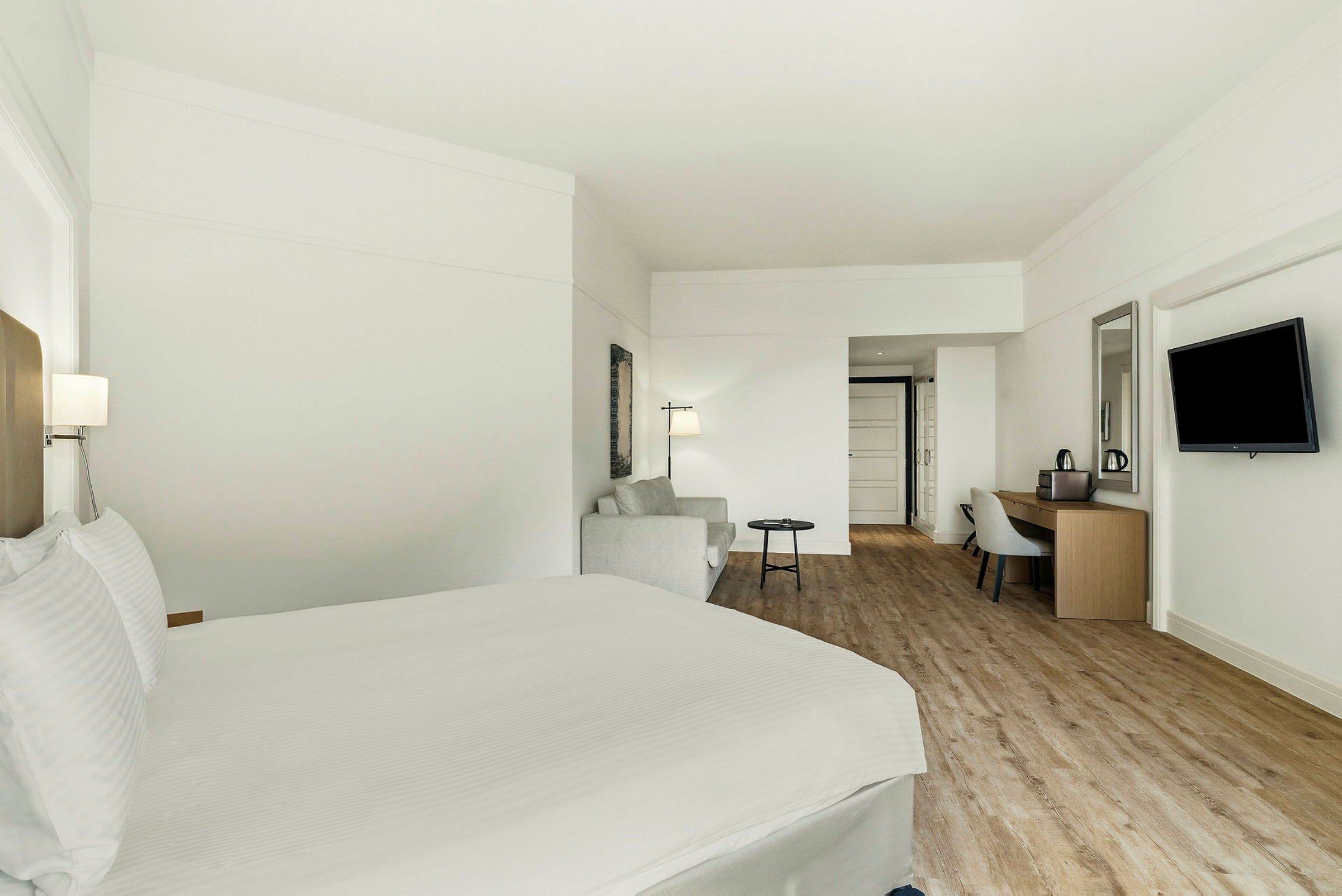 Et hotellrom med en seng, en sittegruppe og et skrivebord. (AI-generert tekst)