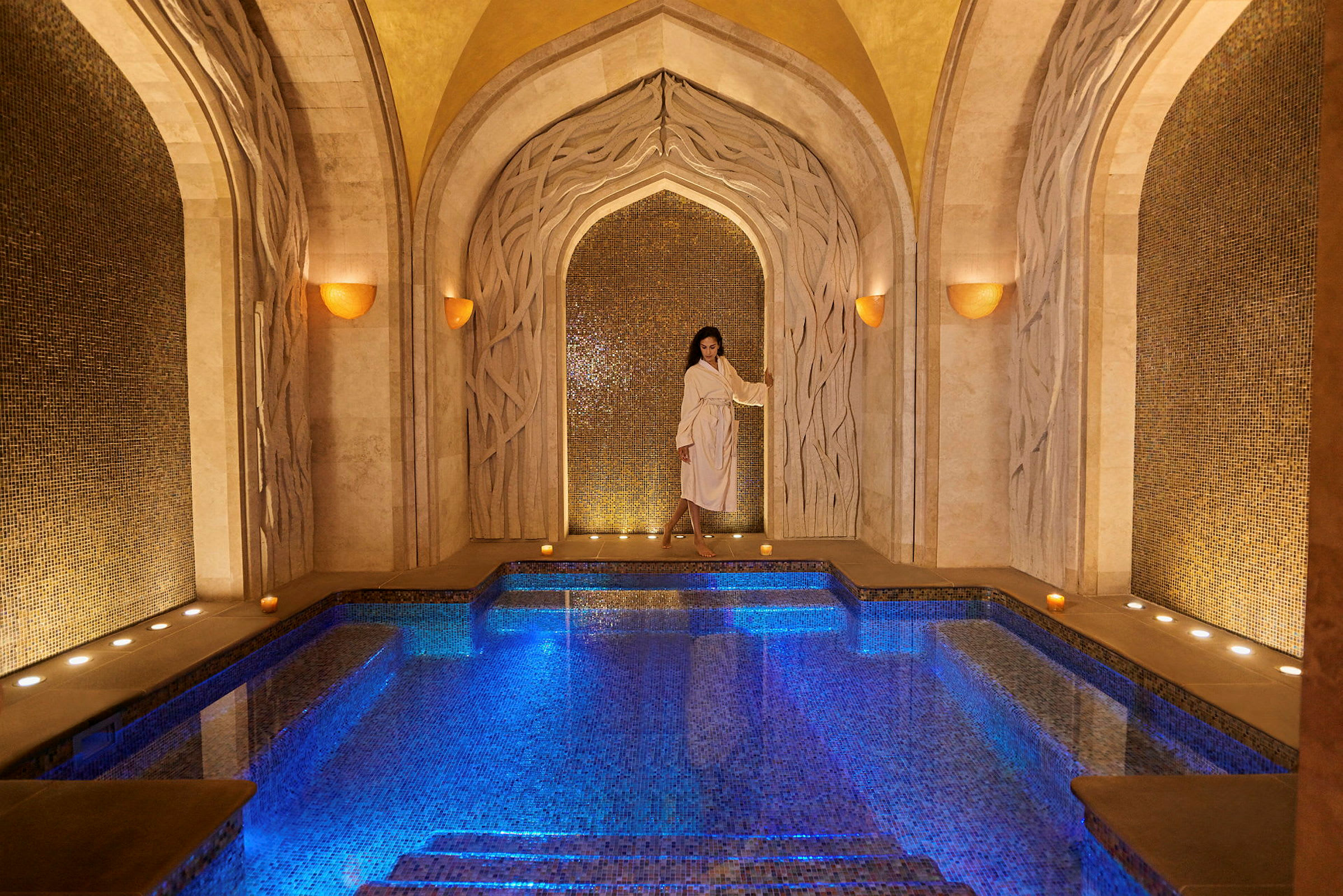 Elegant spa-miljø med opplyst mosaikkbasseng og dekorative buer. (AI-generert tekst)
