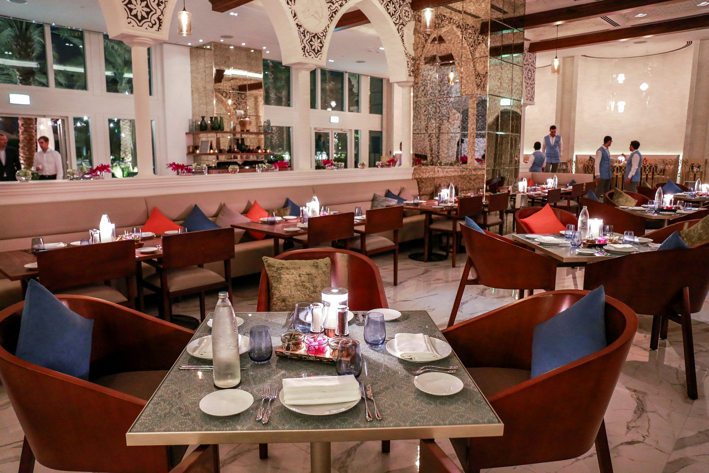 En elegant restaurant med dekket bord, fargede puter og moderne interiørdetaljer. (AI-generert tekst)