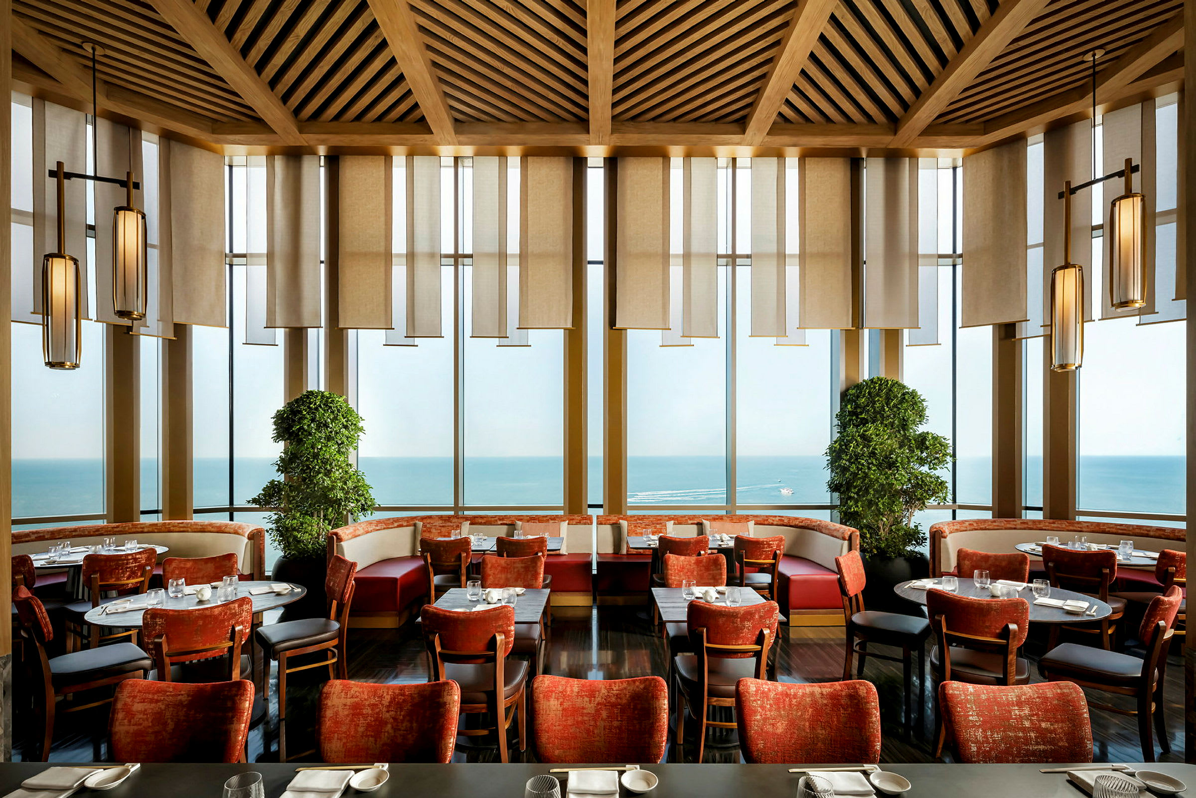 Interiør av en restaurant med røde stoler, panoramavinduer og havutsikt. (AI-generert tekst)
