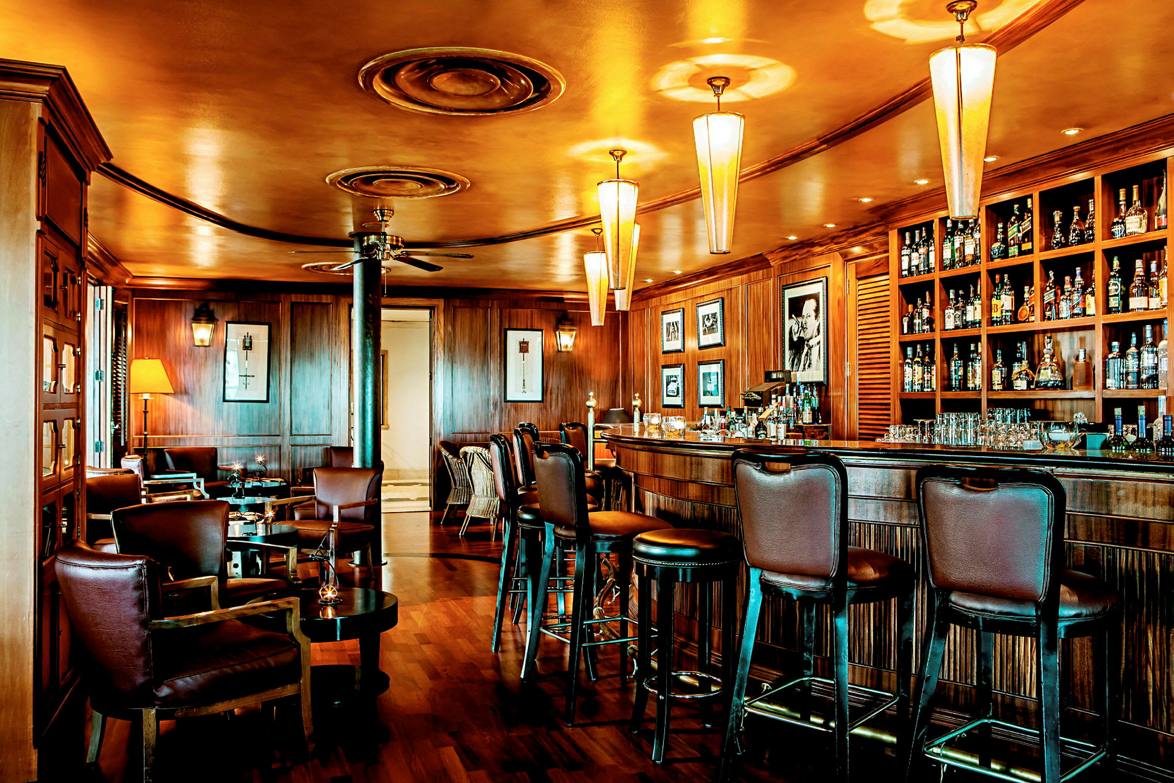 En elegant bar med trevpanel og komfortable stoler. Taklamper lyser opp rommet. (AI-generert tekst)