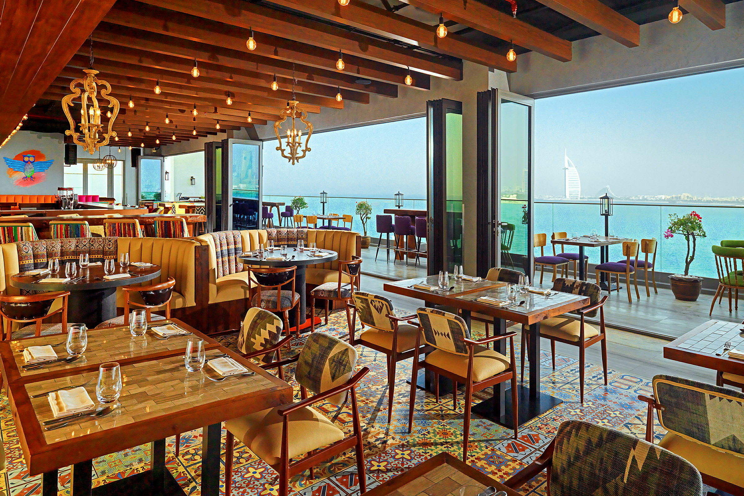 Restaurant med moderne møbler, fargerikt flisegulv og panoramautsikt over havet. (AI-generert tekst)
