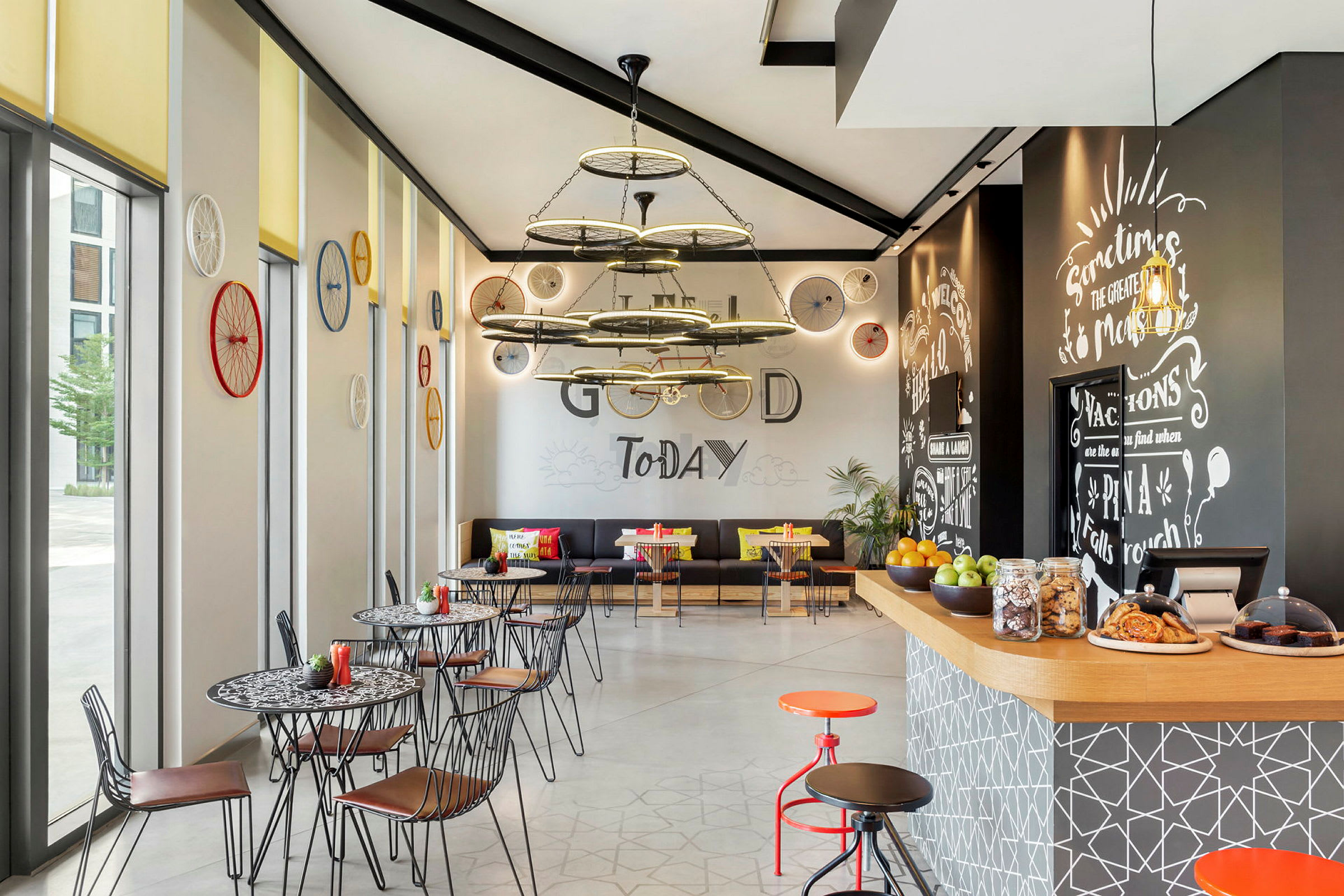 En moderne kafé med kunstnerisk innredning, dekorert med sykkelhjul på veggene og en sentral taklampe i industriell stil. (AI-generert tekst)