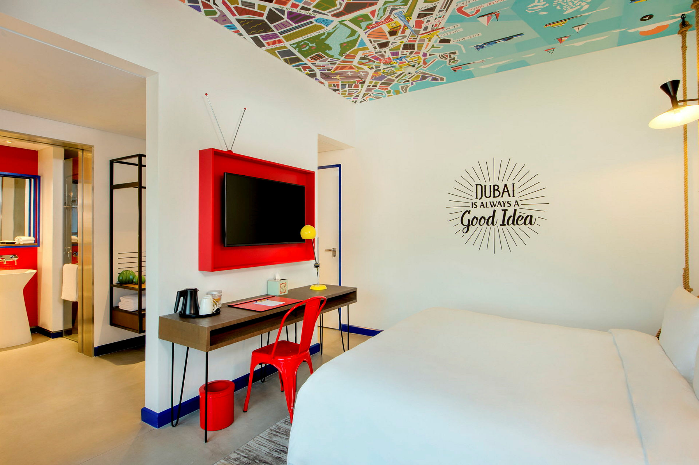 Moderne innredet hotellrom med stor seng, skrivebord med stol og TV på veggen. (AI-generert tekst)