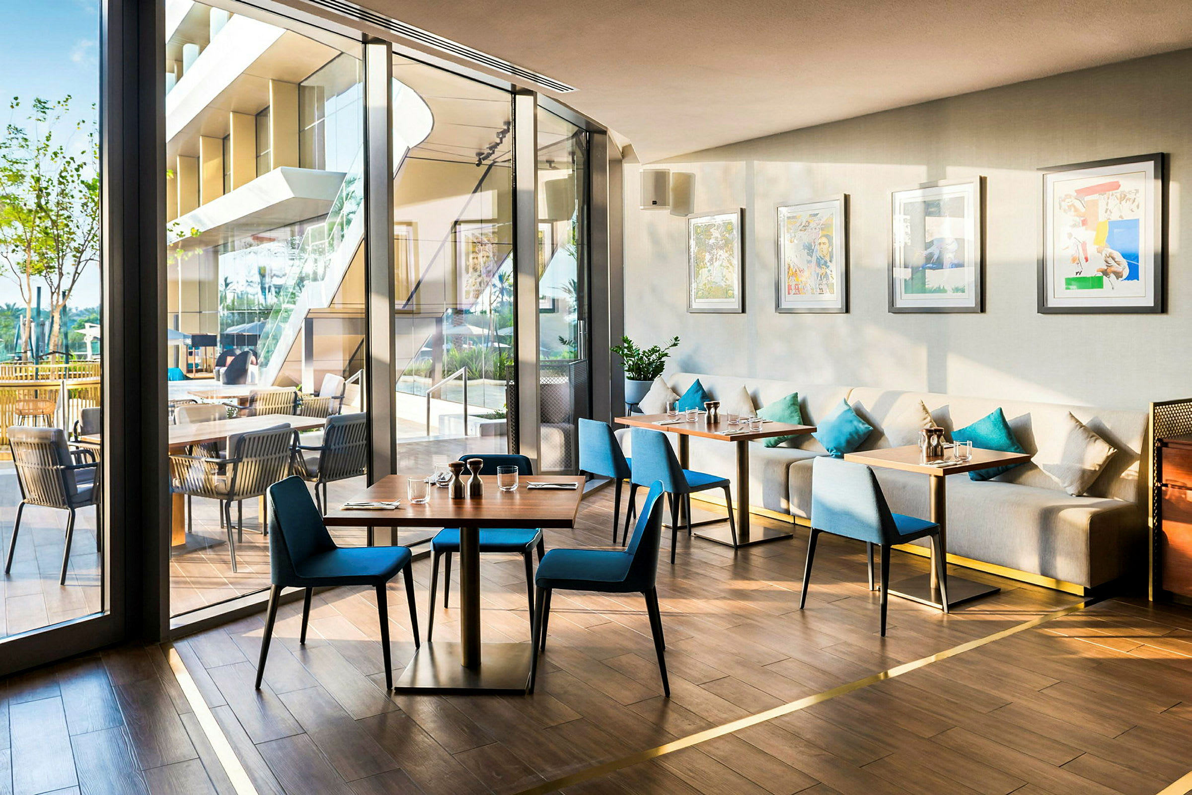 En moderne innredet kafé med bord og stoler, store vinduer og et utendørsområde. (AI-generert tekst)