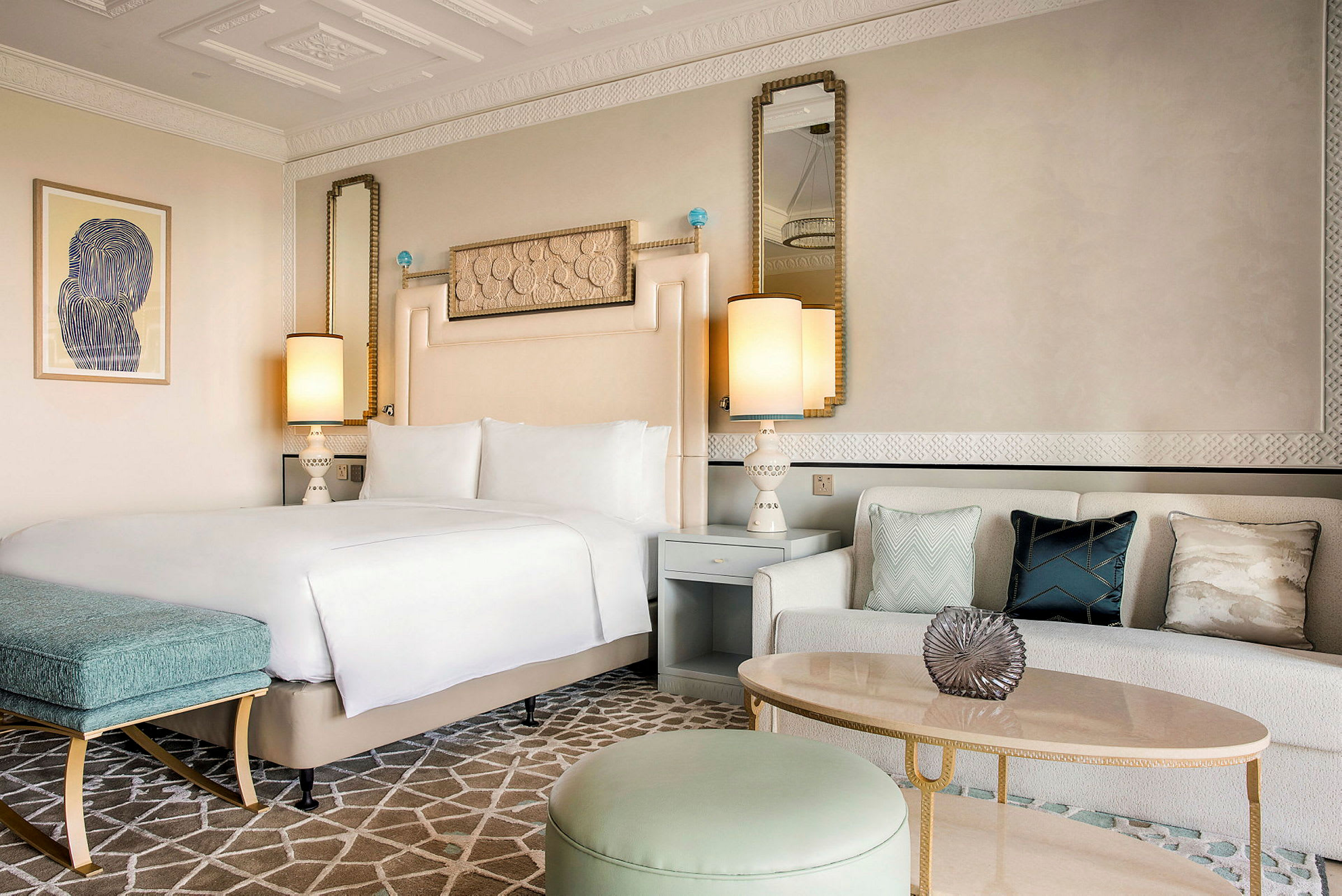 Et elegant hotellrom med en dobbeltseng, en sofa med dekorative puter og et stilfullt bord. (AI-generert tekst)