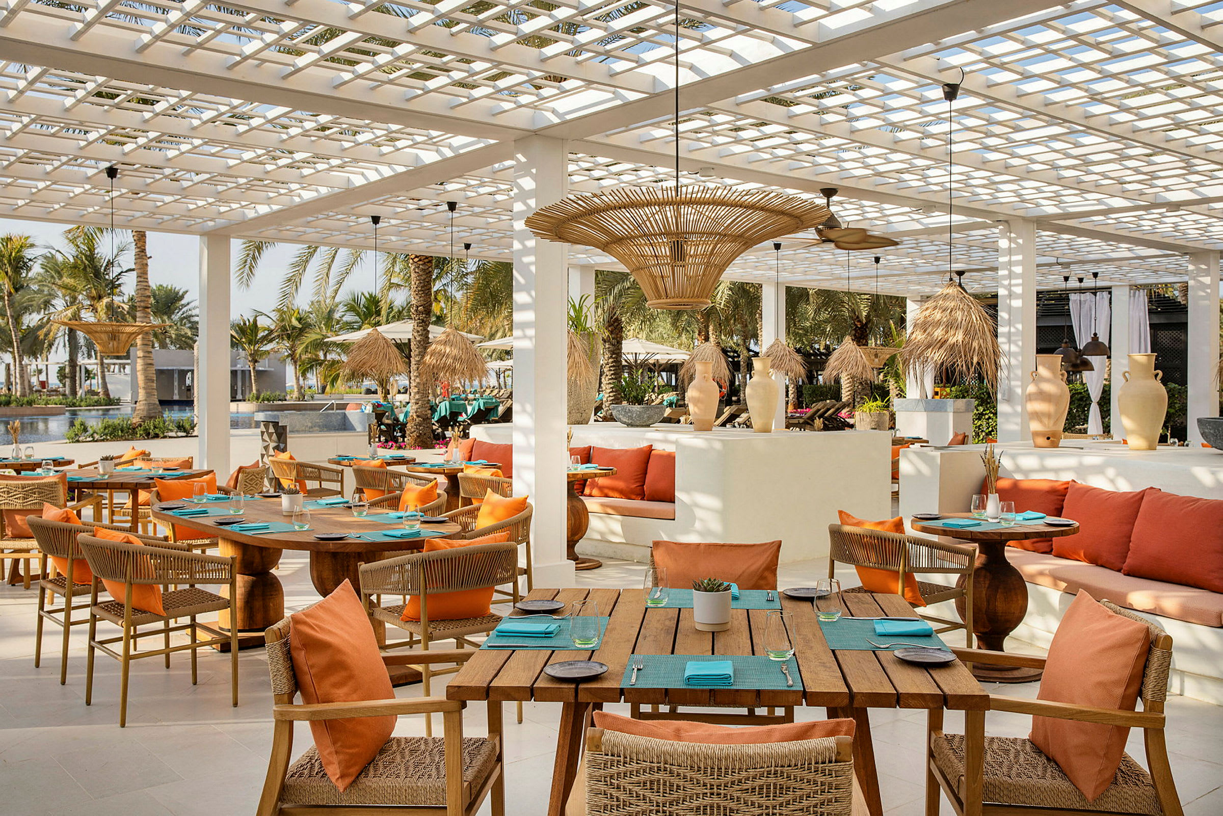 Restaurant med tremøbler og oransje puter på terrasse. (AI-generert tekst)