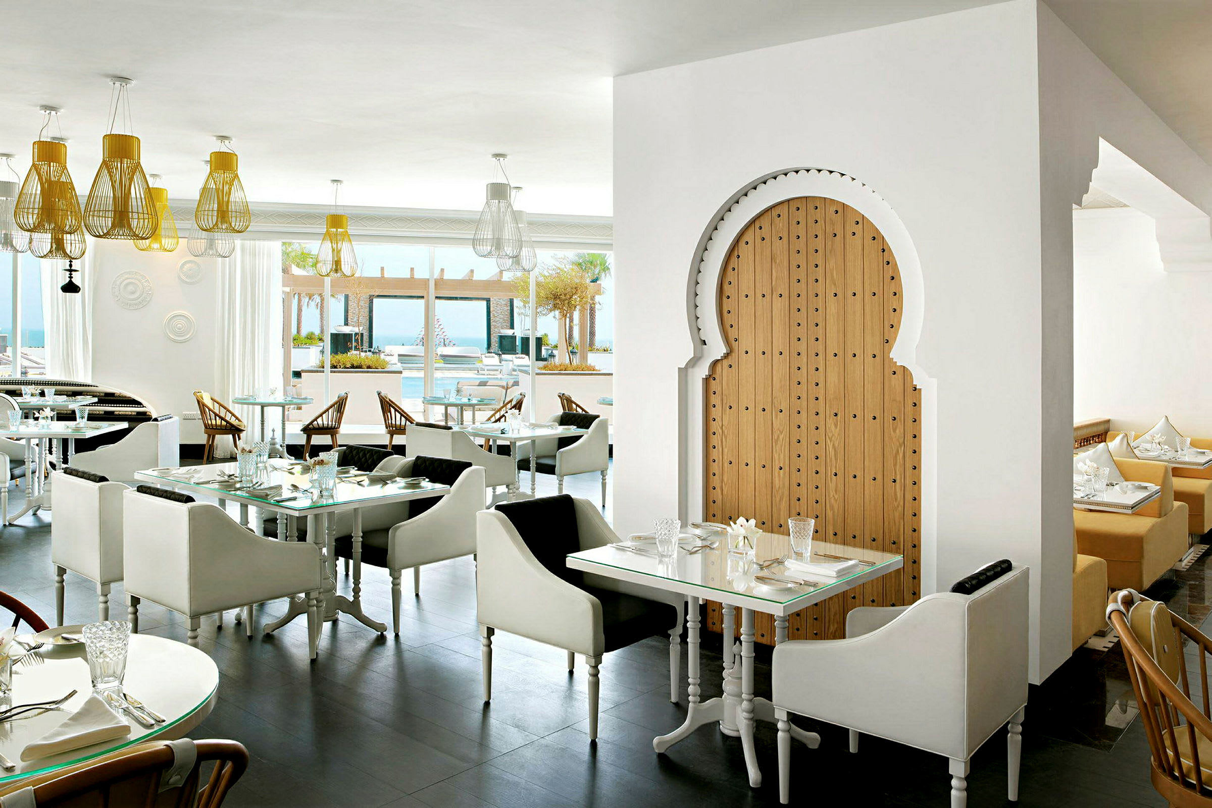 Interiør av en restaurant med moderne og stilfull innredning. Lyse sitteplasser og belysning med en orientalsk tredør. (AI-generert tekst)