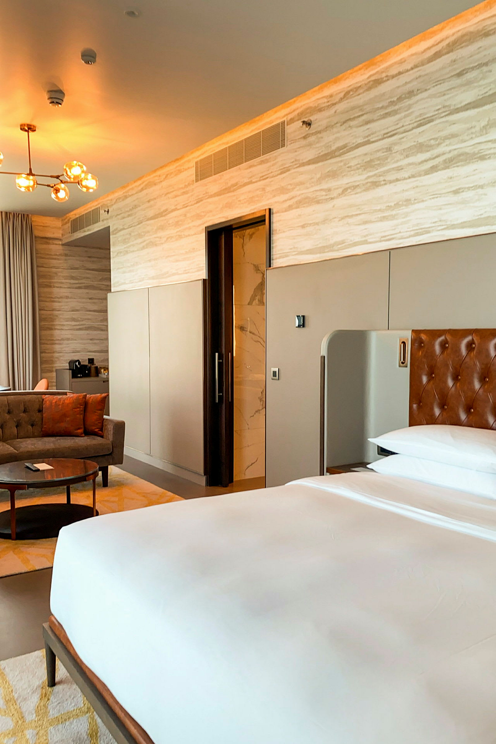 Et moderne hotellrom med en seng, sitteområde og inngang til bad. (AI-generert tekst)