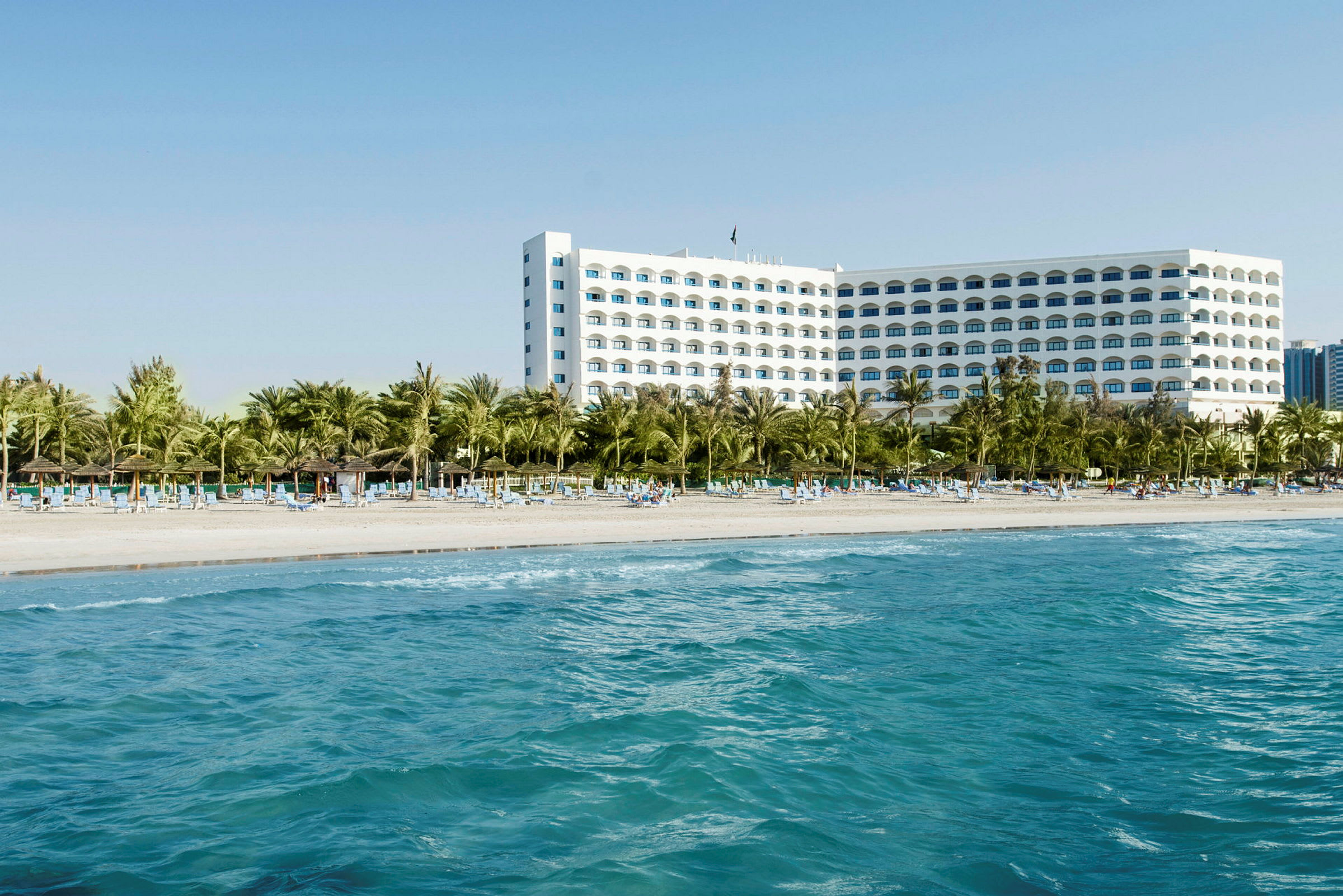Hotell ved stranden med palmer og solsenger. (AI-generert tekst)