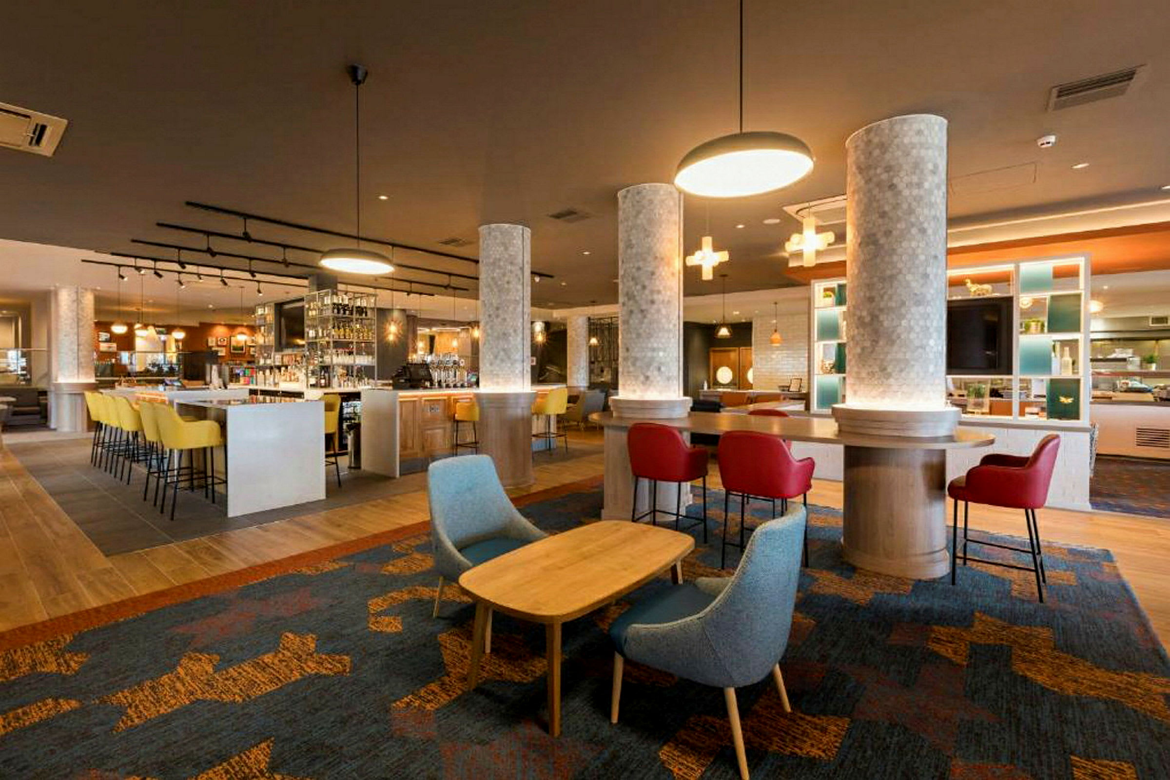 En moderne hotellbar med fargerike stoler og lys. (AI-generert tekst)