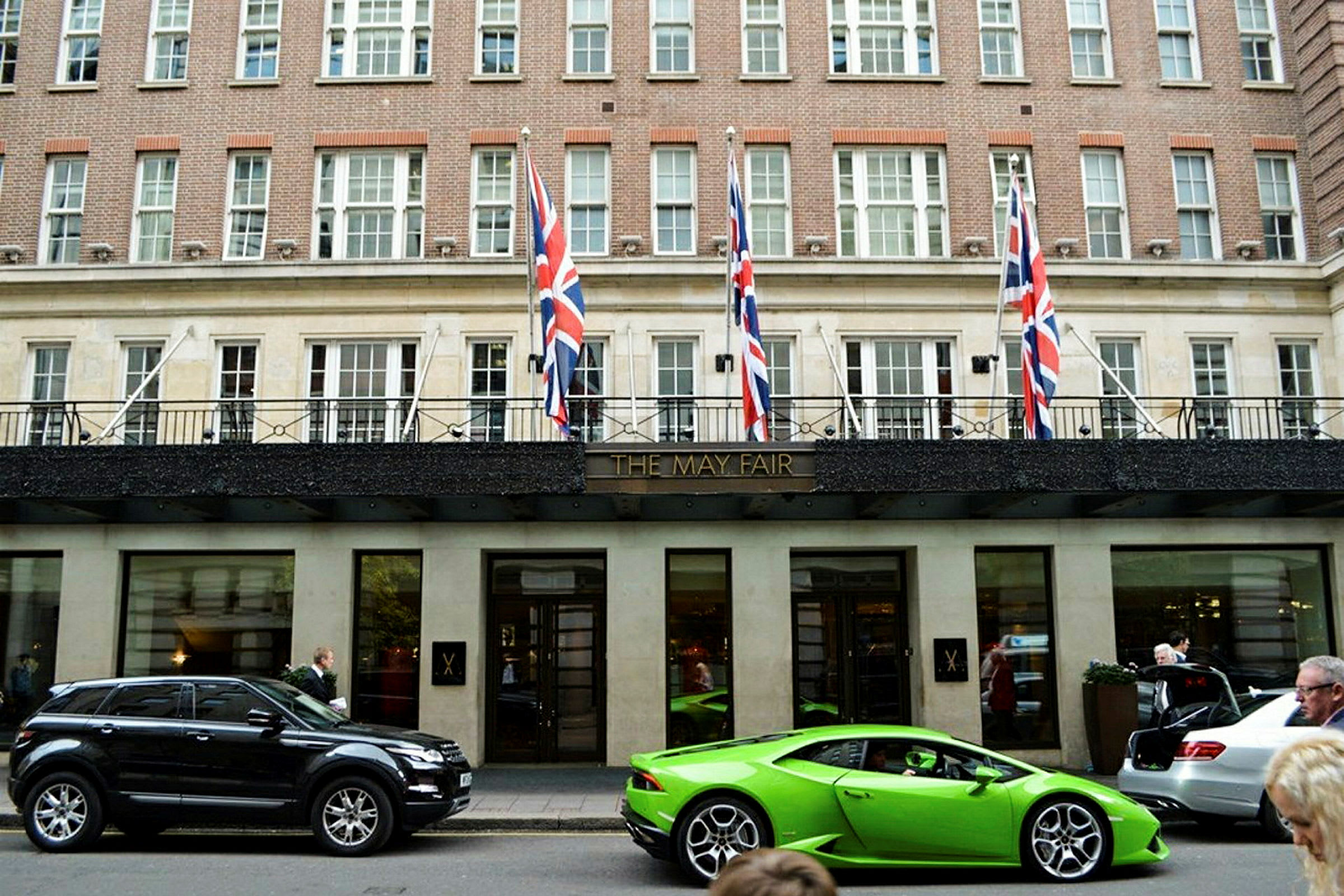 Fasaden til det elegante May Fair Hotel med biler parkert foran. (AI-generert tekst)