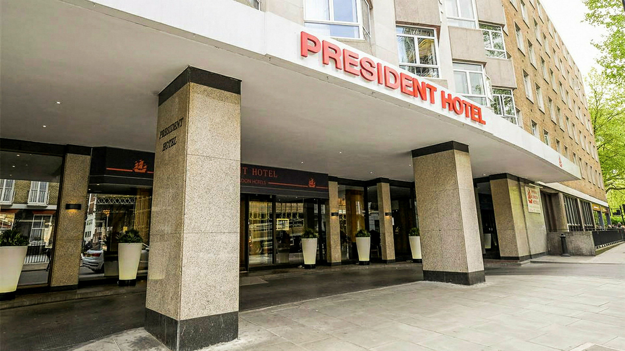 Forsiden av President Hotel med inngang og skilt. (AI-generert tekst)