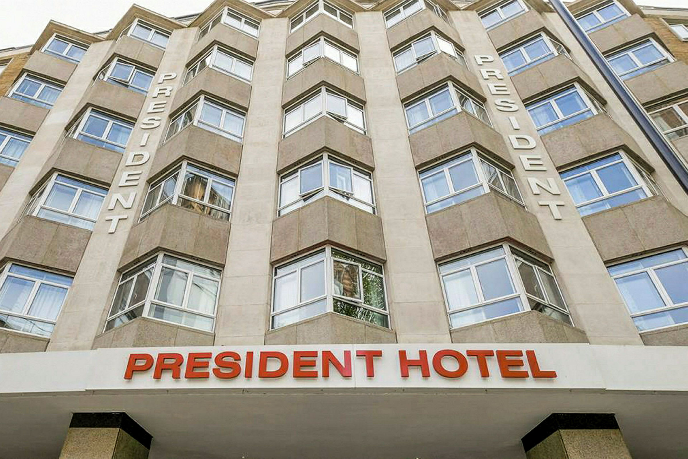 Klassisk fasade av President Hotel med store vinduer og teksten 'President' på veggen. (AI-generert tekst)