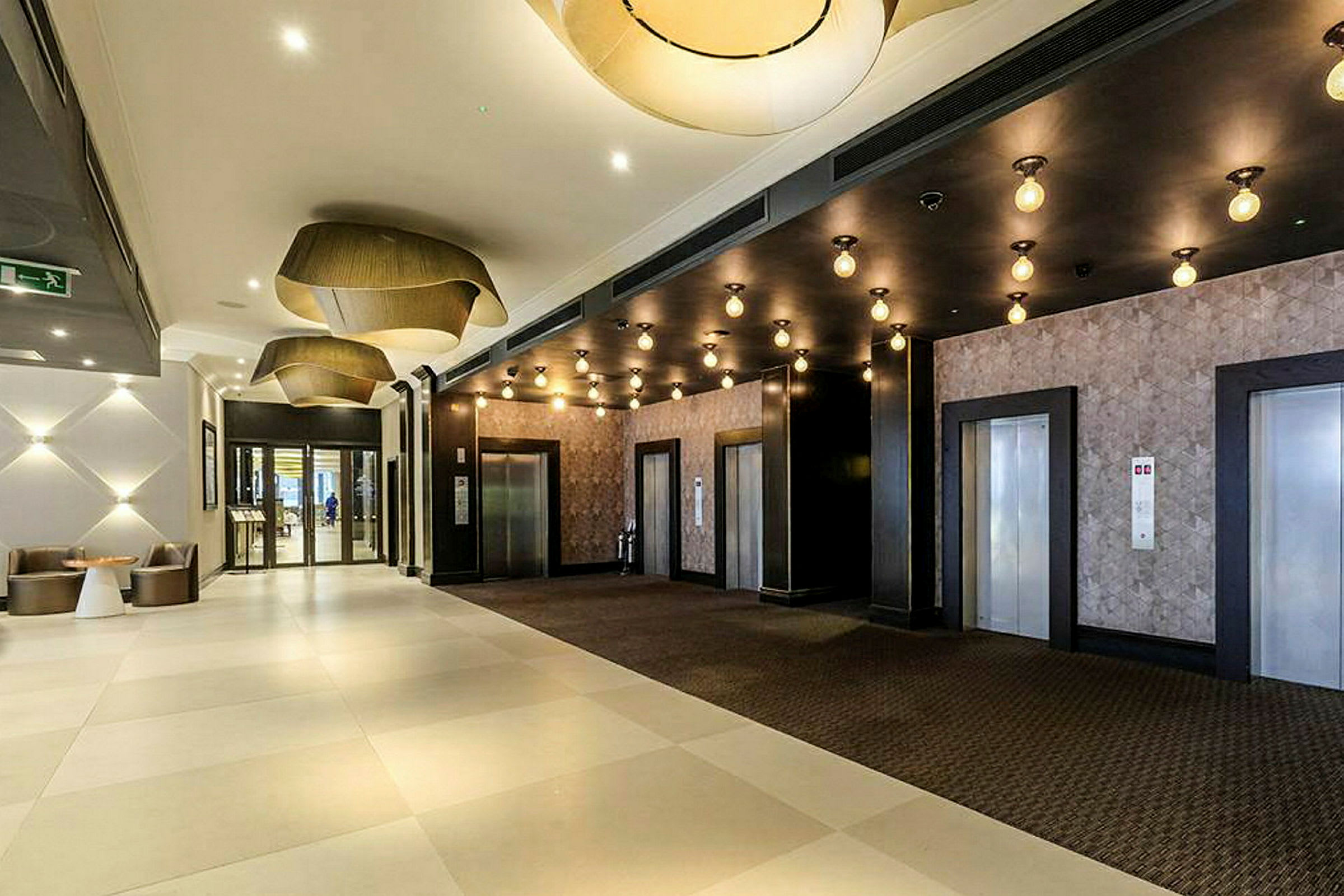 Hotellobby med tre heisdører og moderne armaturer. (AI-generert tekst)
