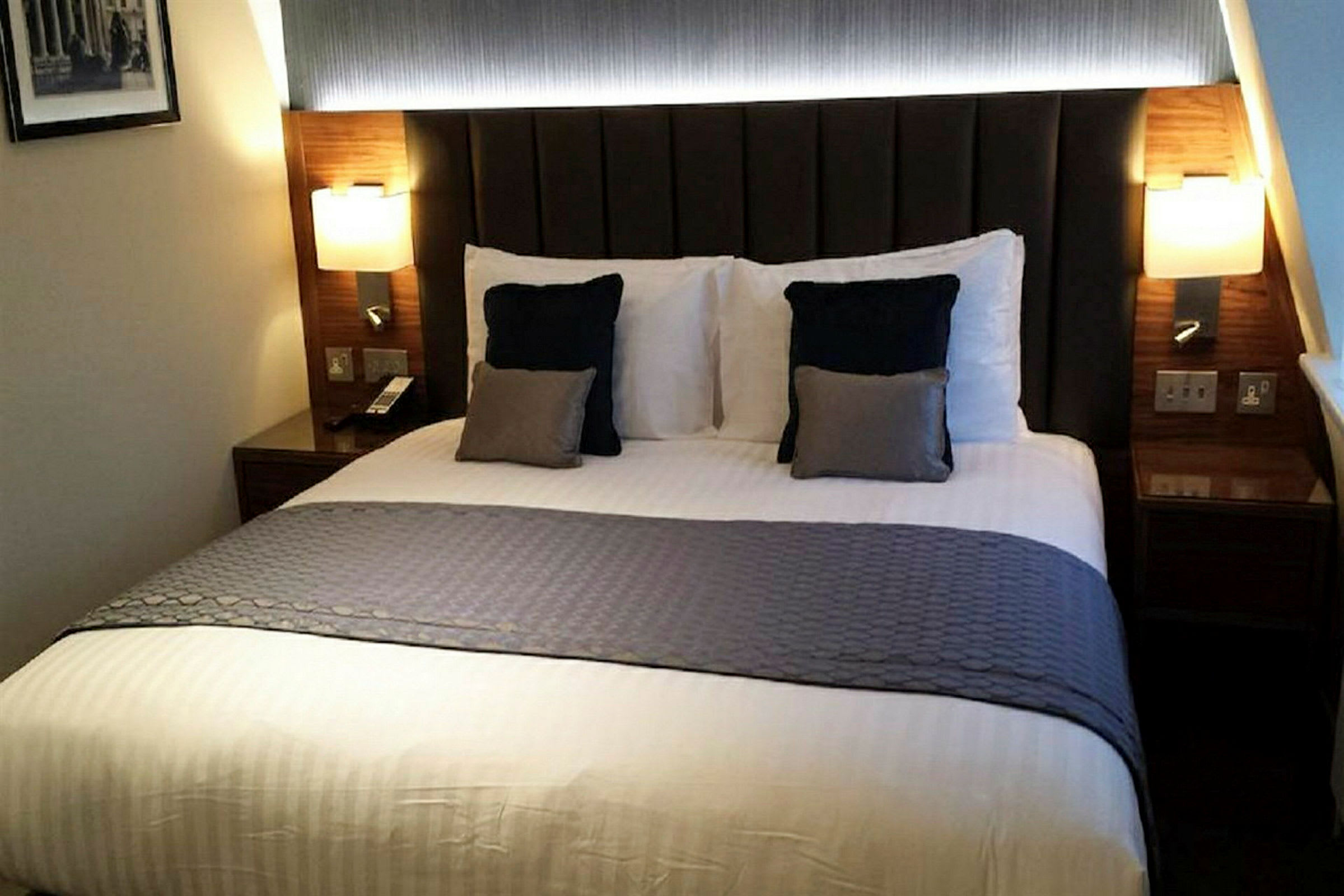 En seng på et hotellrom med puter og et sengeteppe. (AI-generert tekst)