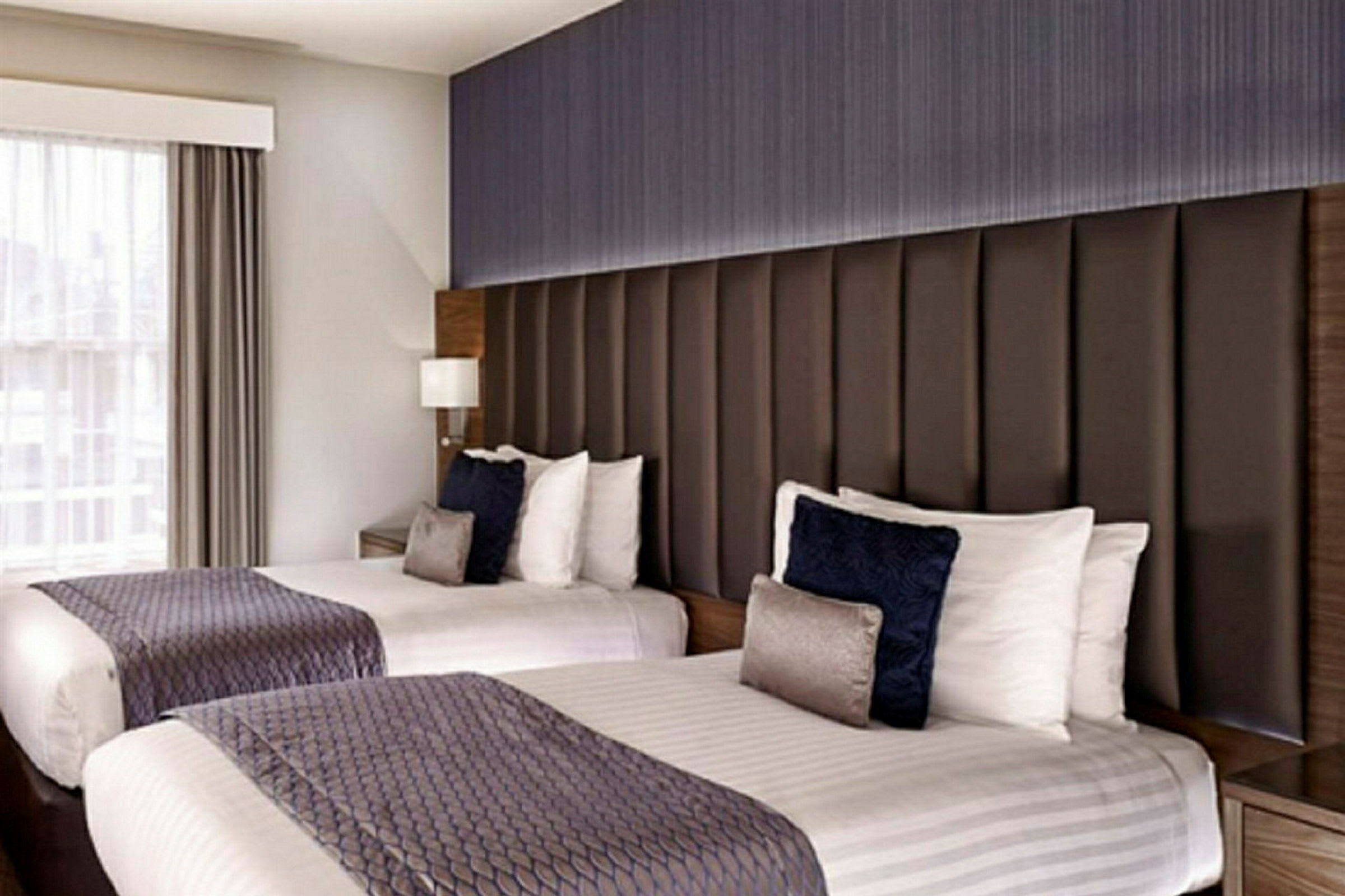 Bilde av to enkeltsenger med dekorative puter på et hotellrom. (AI-generert tekst)