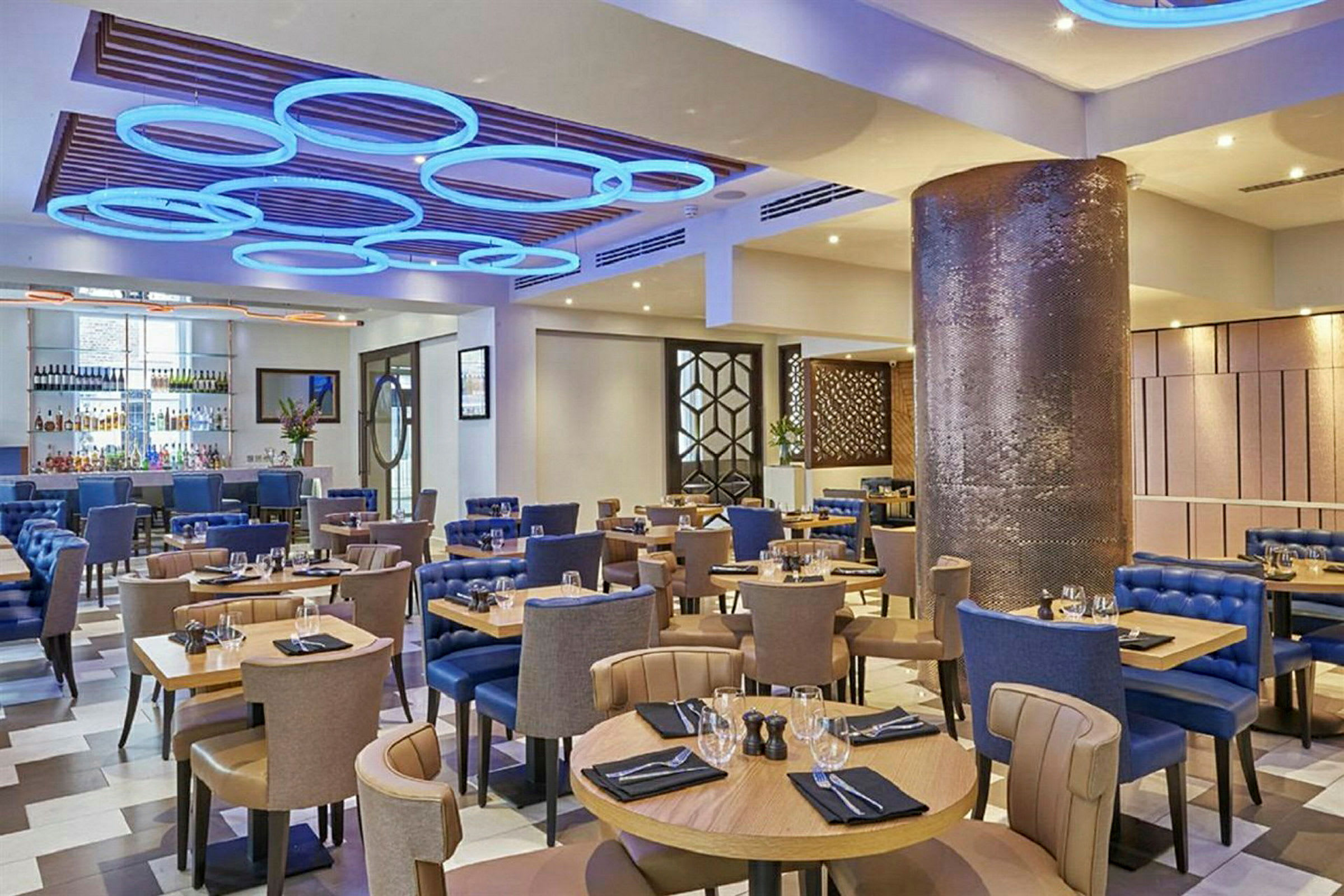En restaurant med bord og stoler, moderne innredning og dekorativ belysning. (AI-generert tekst)