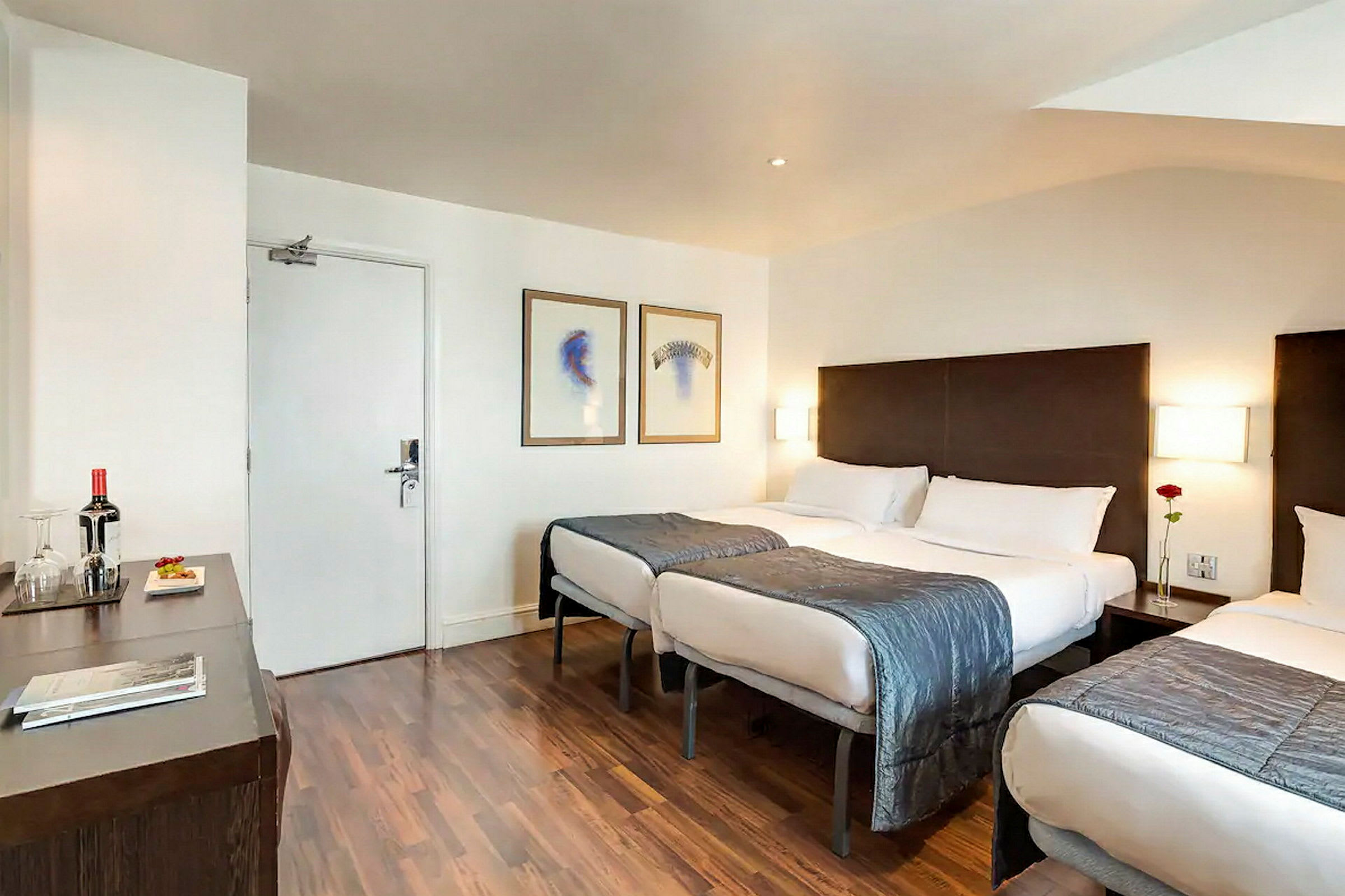Hotellrom med tre senger og moderne innredning. (AI-generert tekst)