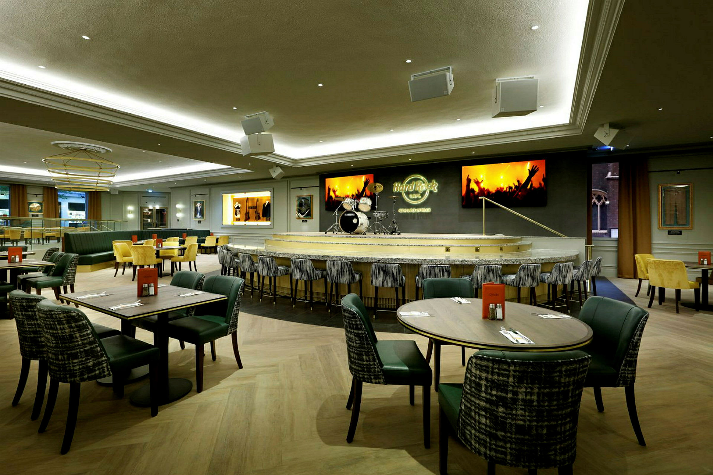Bilde av et Hard Rock Cafe med bordservering og en scene med trommesett. (AI-generert tekst)