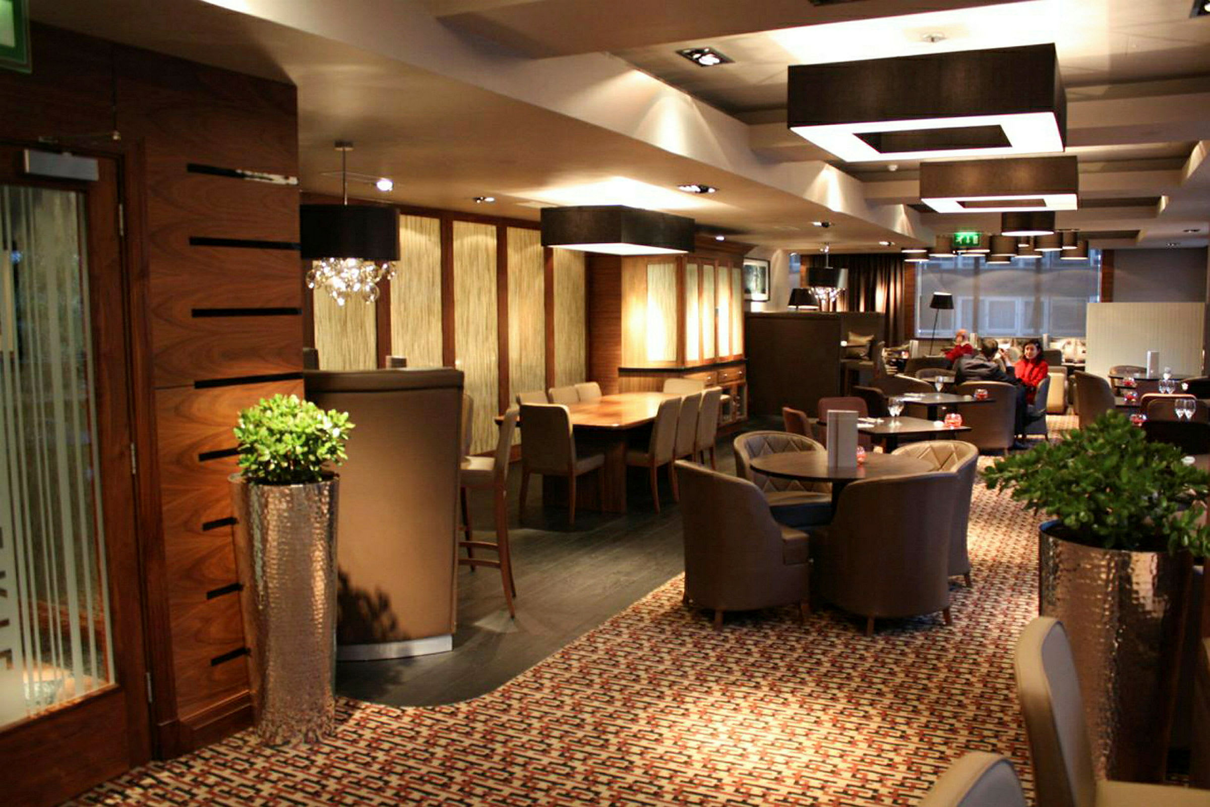 Interiør av en restaurant eller lounge med bord, stoler og elegant dekorasjon. (AI-generert tekst)