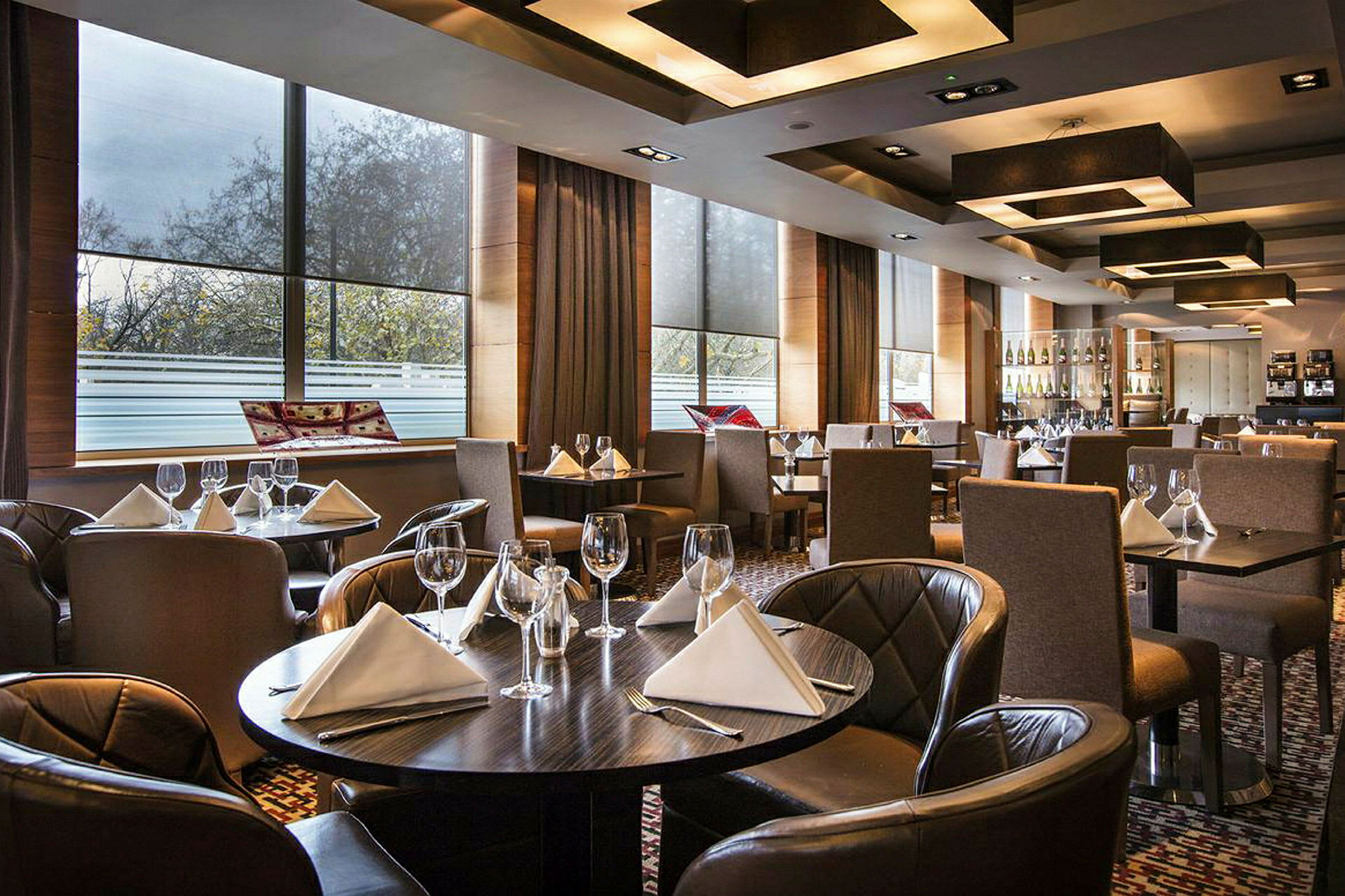 En elegant restaurant med dekkede bord med hvite servietter og vinglass. (AI-generert tekst)