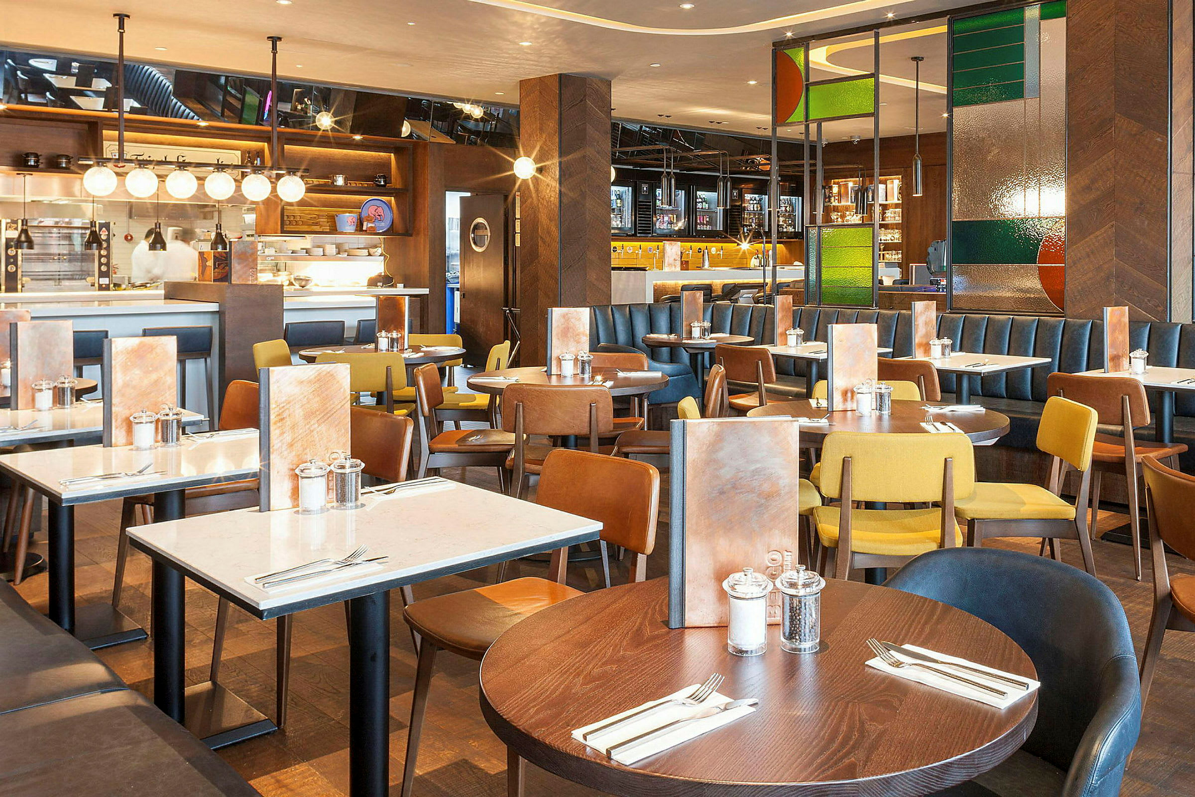 Restaurant med flere spisebord og stoler i forskjellige farger. (AI-generert tekst)