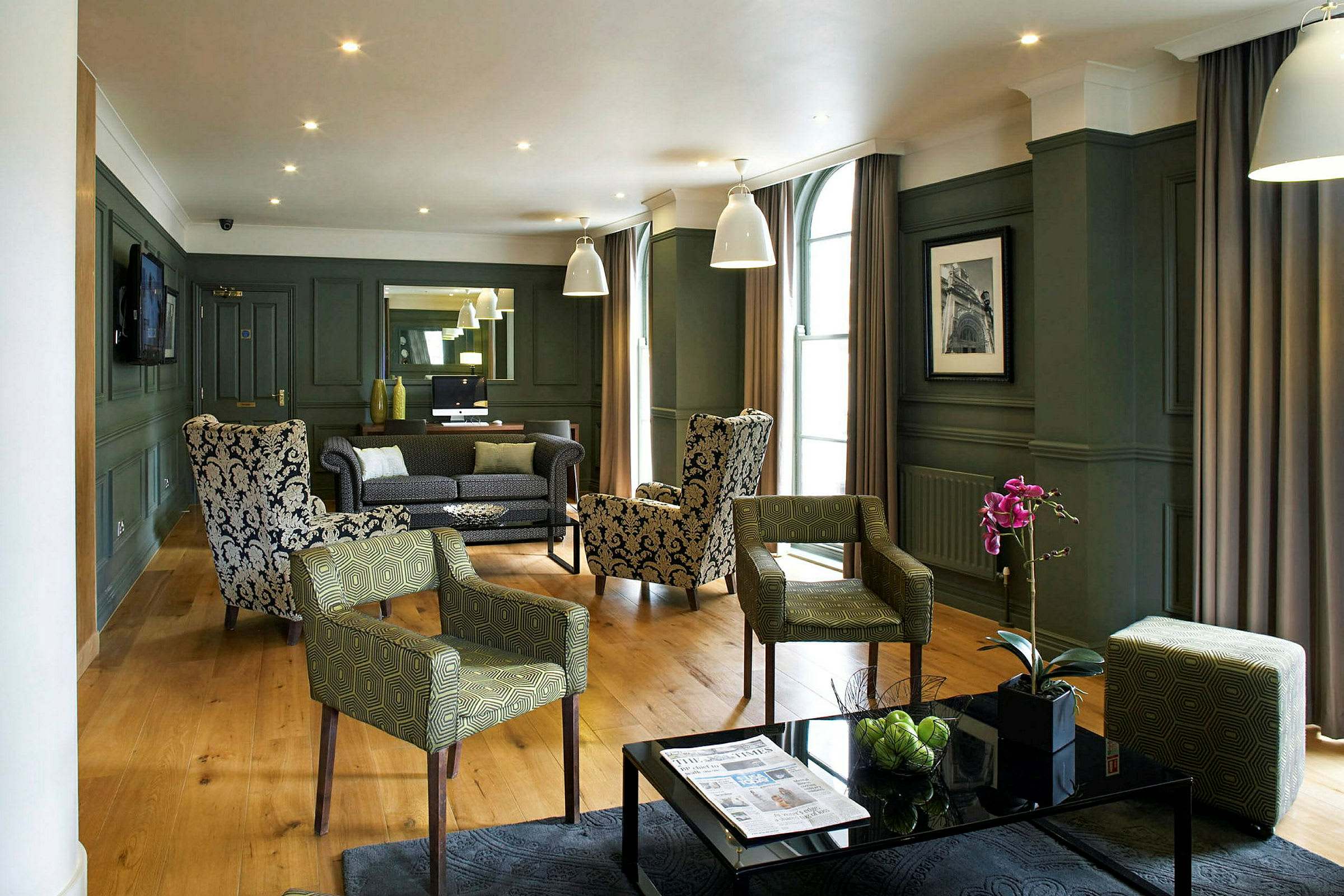 En elegant hotellounge med lenestoler og sofaer, pynteplanter og moderne interiør. (AI-generert tekst)