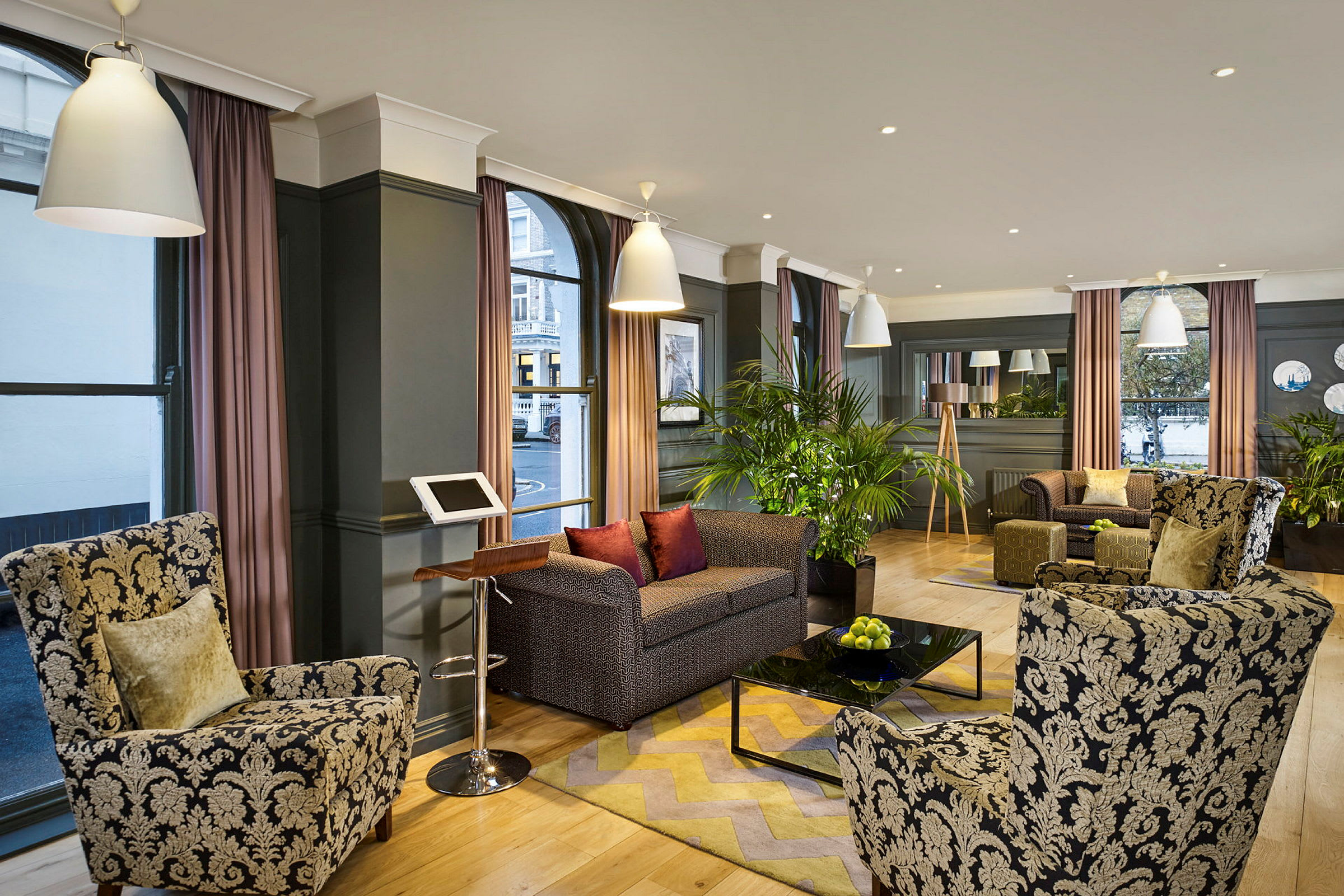 En hotellobby med lenestoler og sofaer rundt et salongbord samt dekorasjon med planter. (AI-generert tekst)