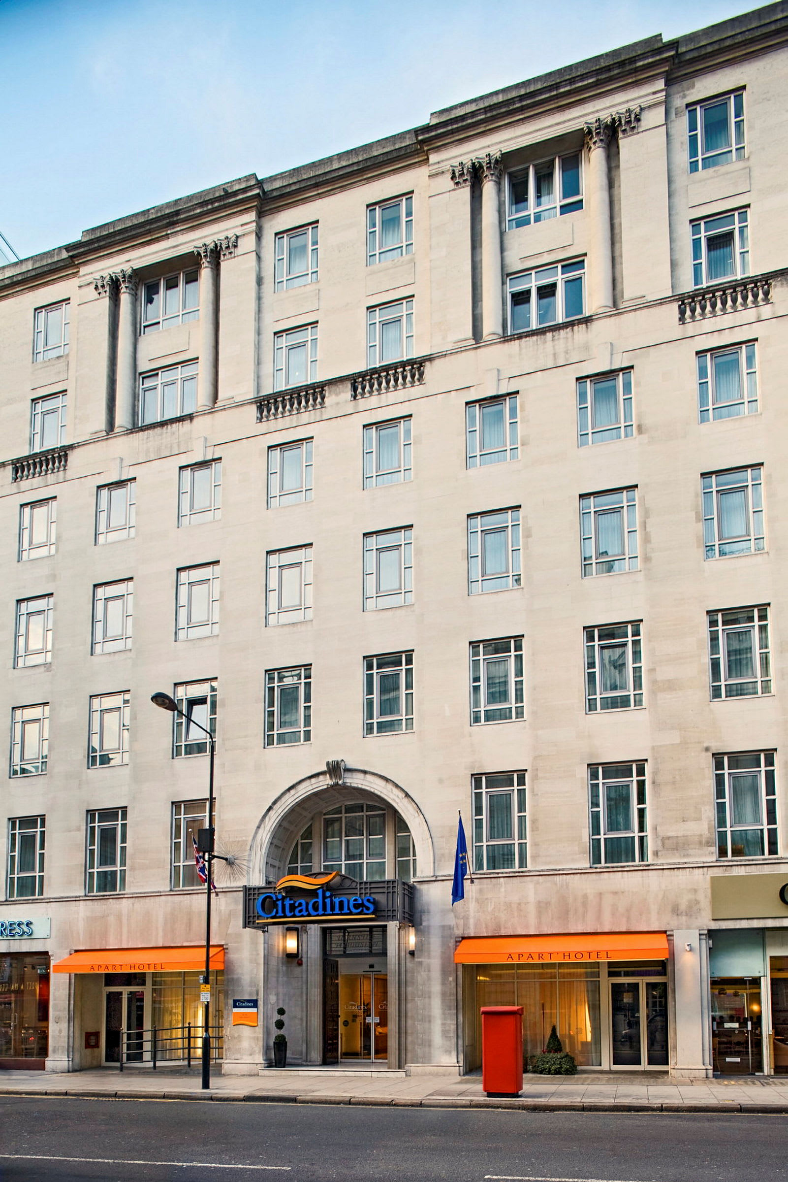 En fleretasjes bygning med navnet Citadines og innganger til et hotell og butikker. (AI-generert tekst)