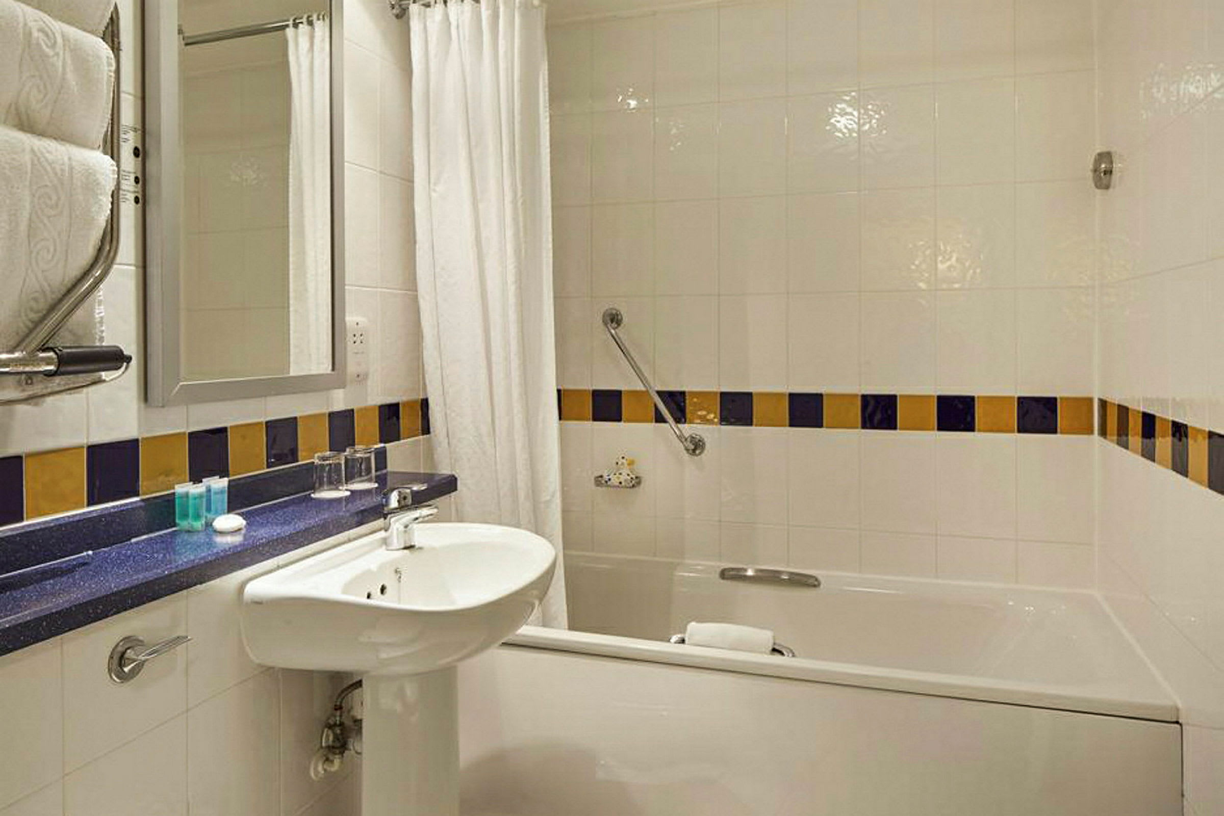 Hotellbad med badekar, servant og speil. (AI-generert tekst)