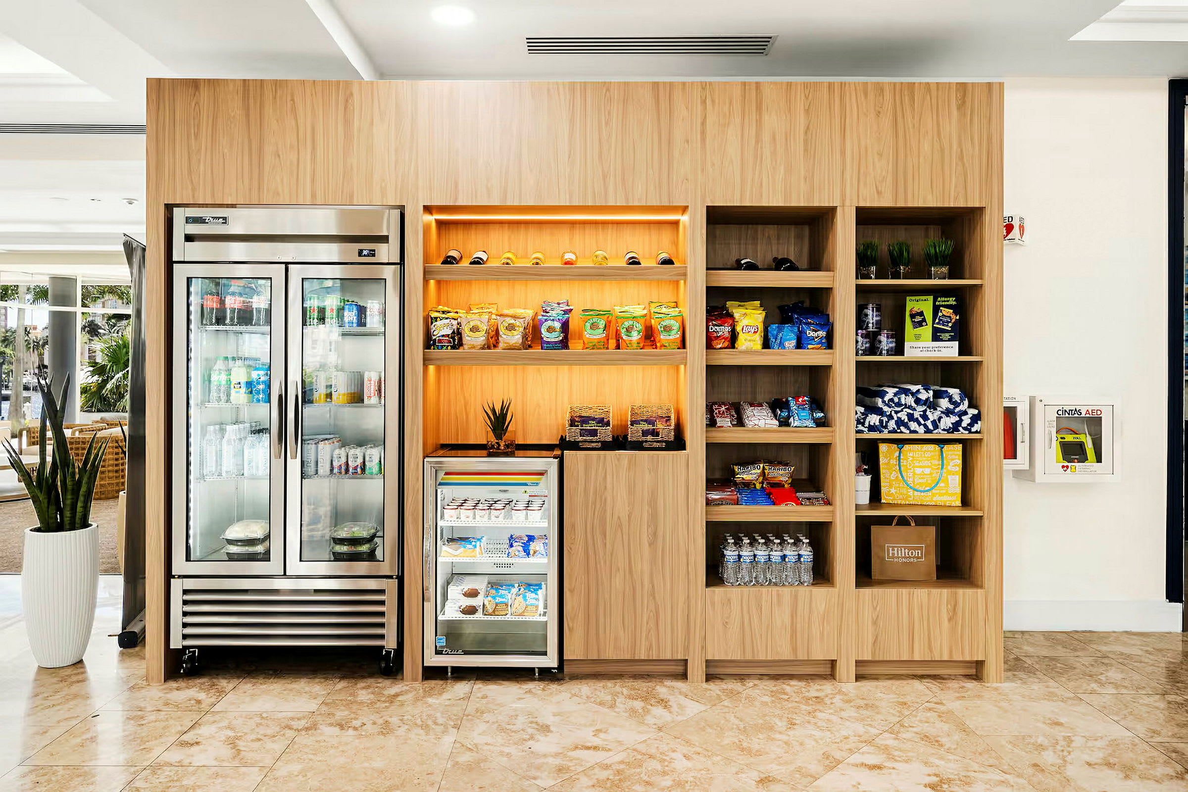 En moderne kiosk med et kjøleskap, hyller med snacks og drikkevarer samt andre varer. (AI-generert tekst)