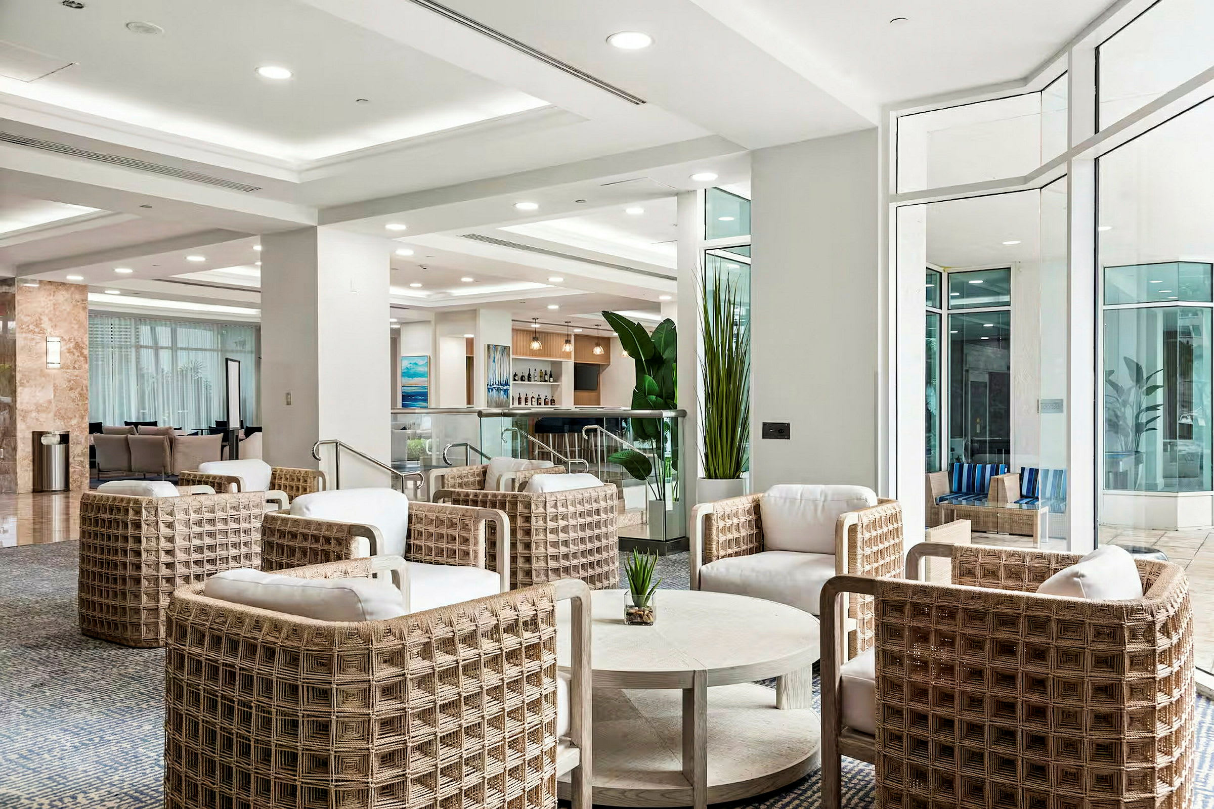 En moderne hotellobby med sittegrupper i lyse farger og store vinduer. (AI-generert tekst)