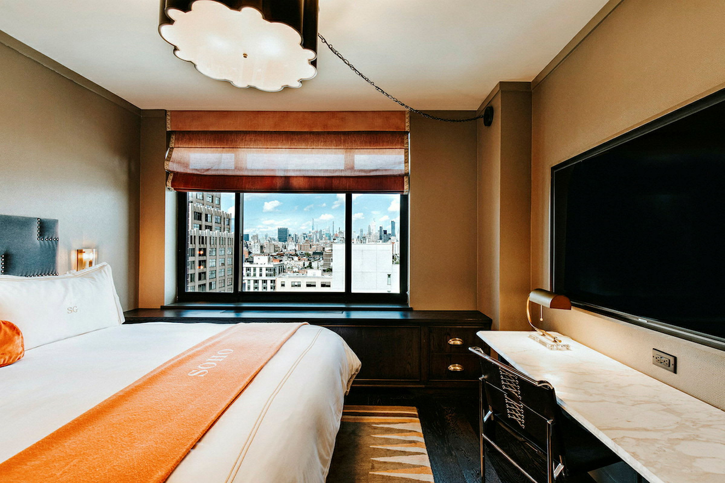 Et moderne hotellrom med en stor seng, et skrivebord og et stort vindu med utsikt over byen. (AI-generert tekst)