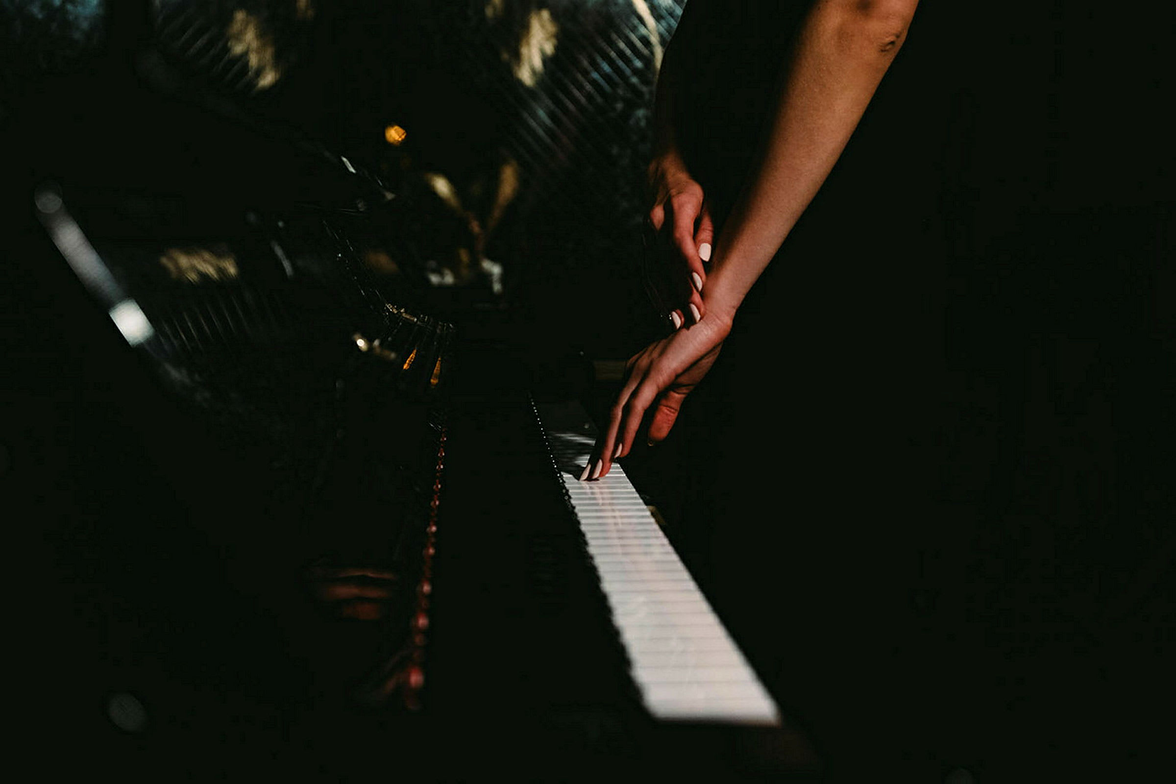 En hånd plassert på et piano i et mørkt rom. (AI-generert tekst)