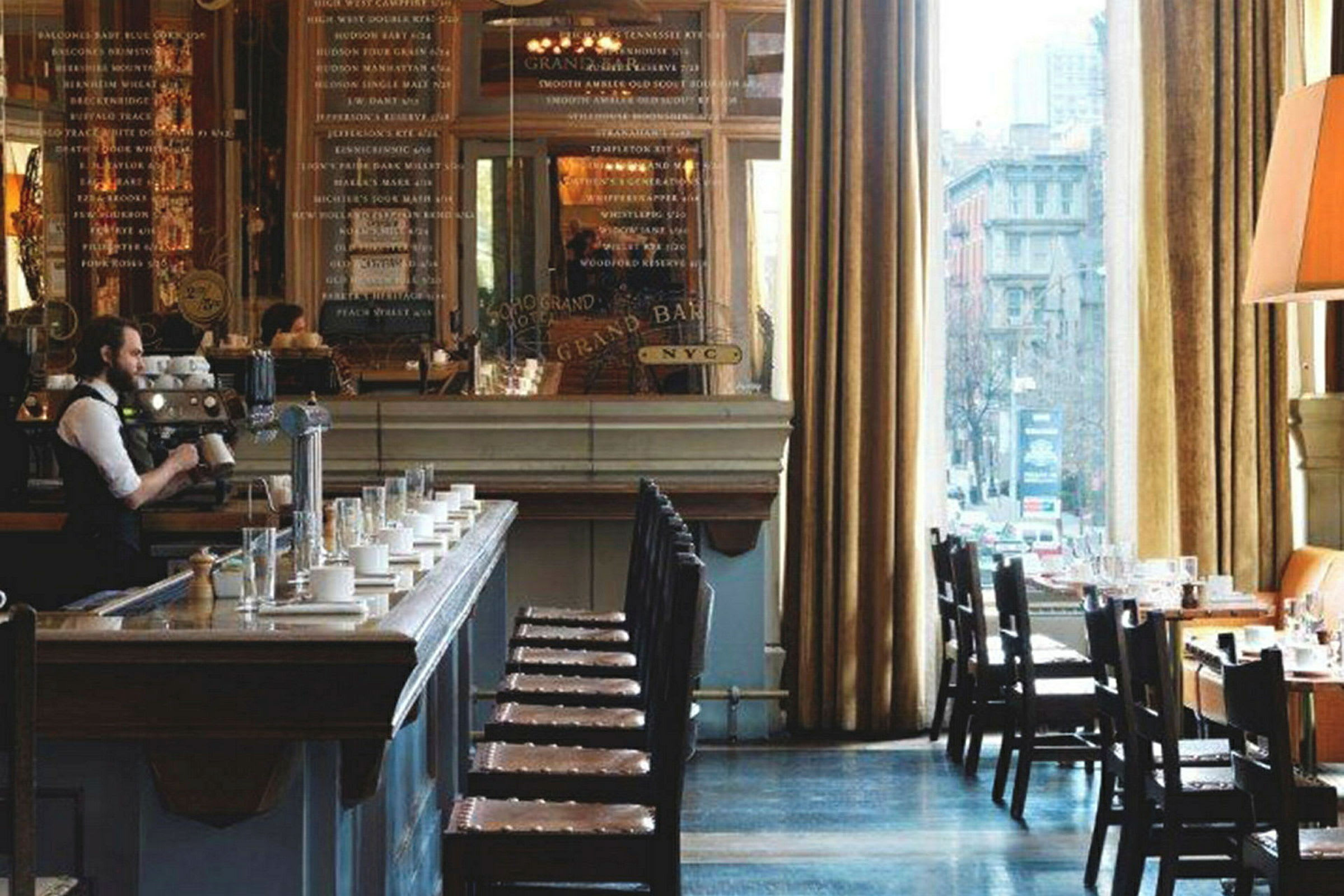 Bilde av et stilfullt innredet kafemiljø med en kaffebar, sitteplasser og store vinduer som slipper inn naturlig lys. (AI-generert tekst)