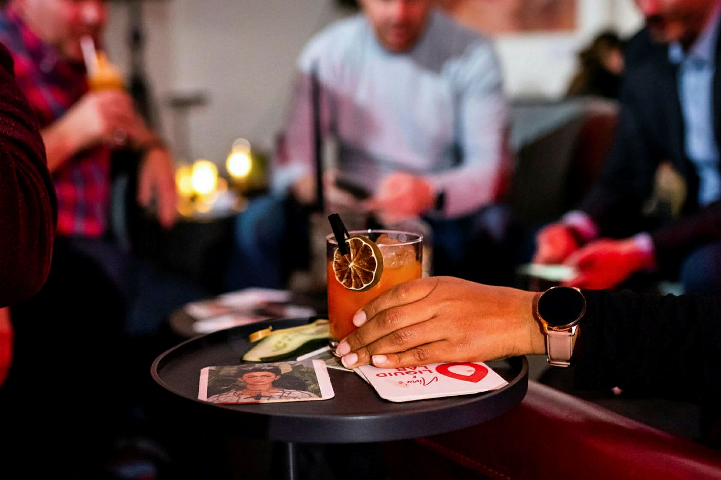 Folk samlet rundt et bord med drinker og drinktilbehør. (AI-generert tekst)