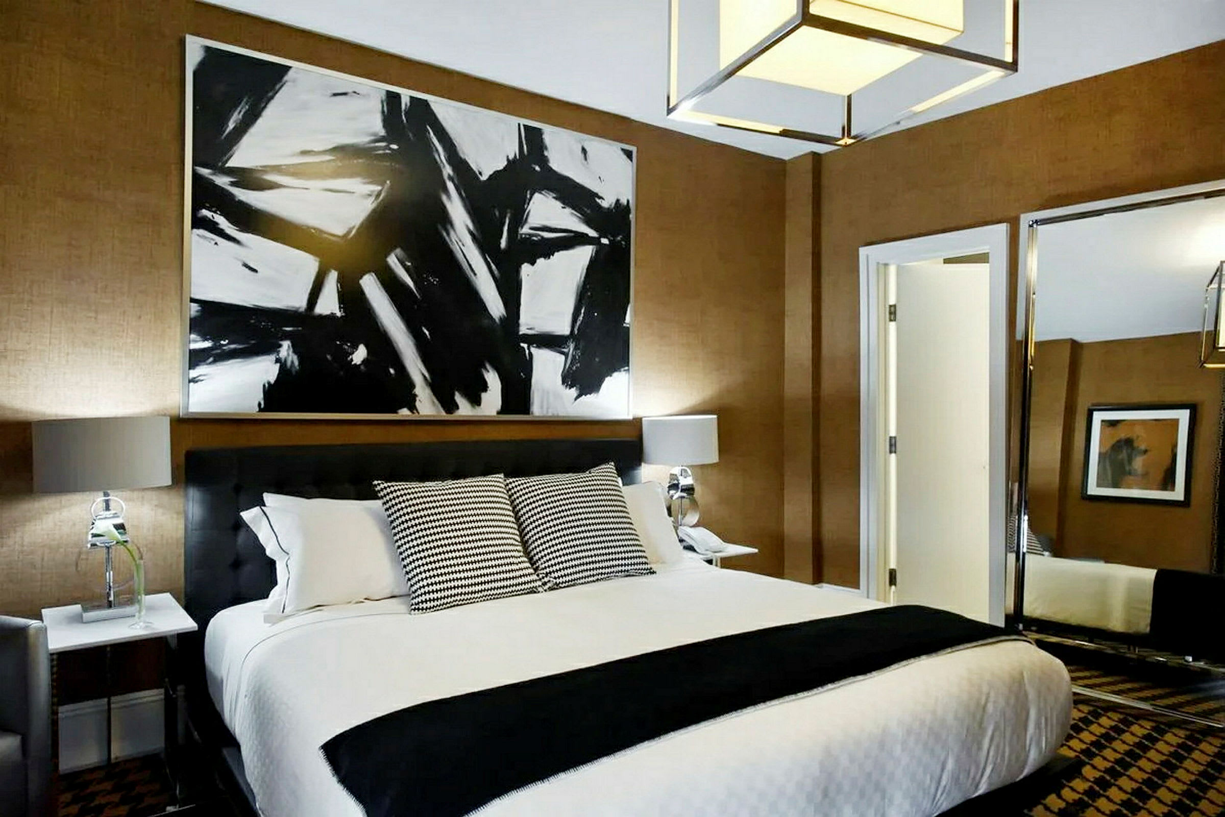 Et hotellrom med en seng, pyntputer og kunst på veggen. (AI-generert tekst)