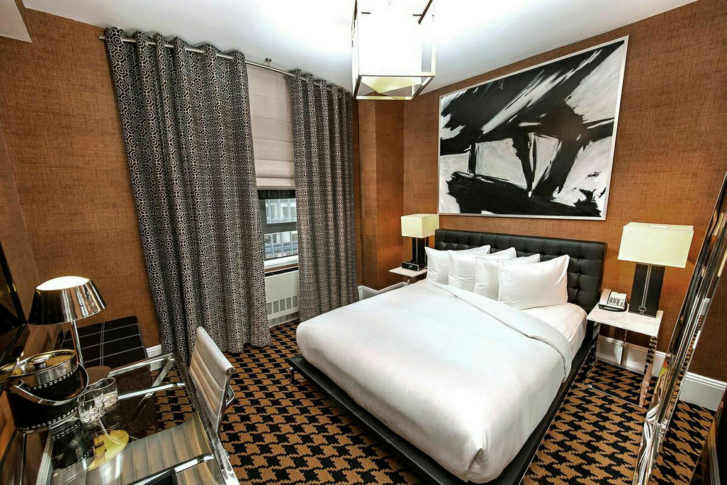 Hotellrom med moderne innredning, en stor seng, skrivebord og abstrakt kunst på veggen. (AI-generert tekst)