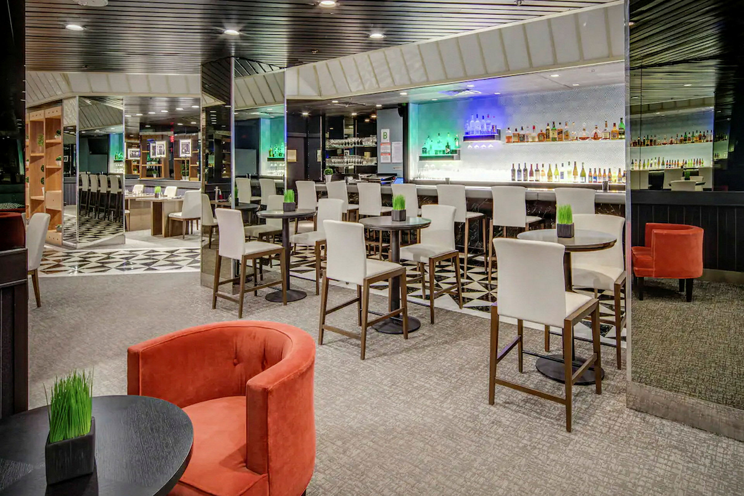 Interiør av en moderne bar med høye stoler ved runde bord og en bardisk i bakgrunnen. (AI-generert tekst)
