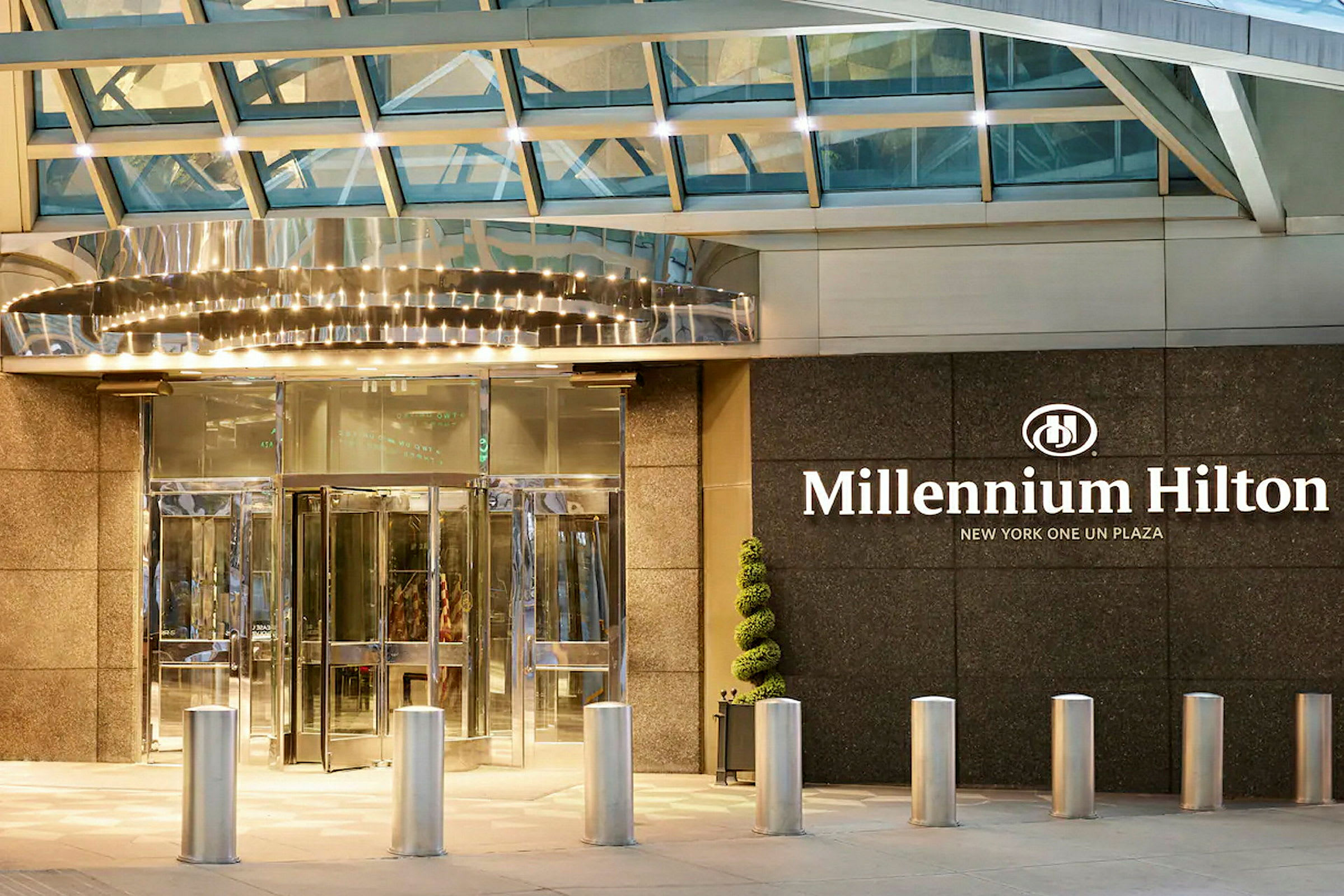 Inngangen til hotellet Millennium Hilton med glassdører og skilt. (AI-generert tekst)