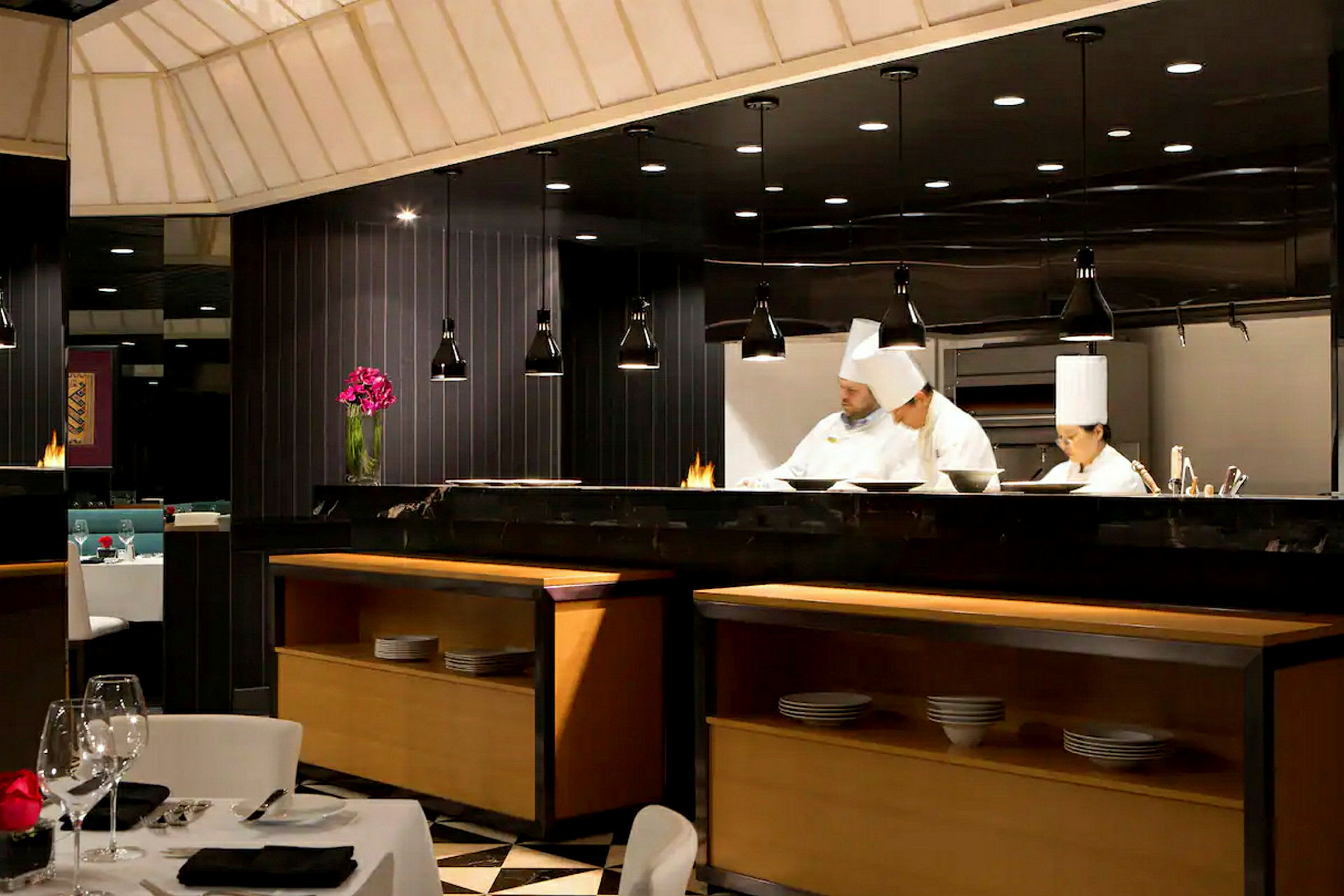 Et elegant restaurantinteriør med et åpent kjøkken hvor kokker arbeider. (AI-generert tekst)
